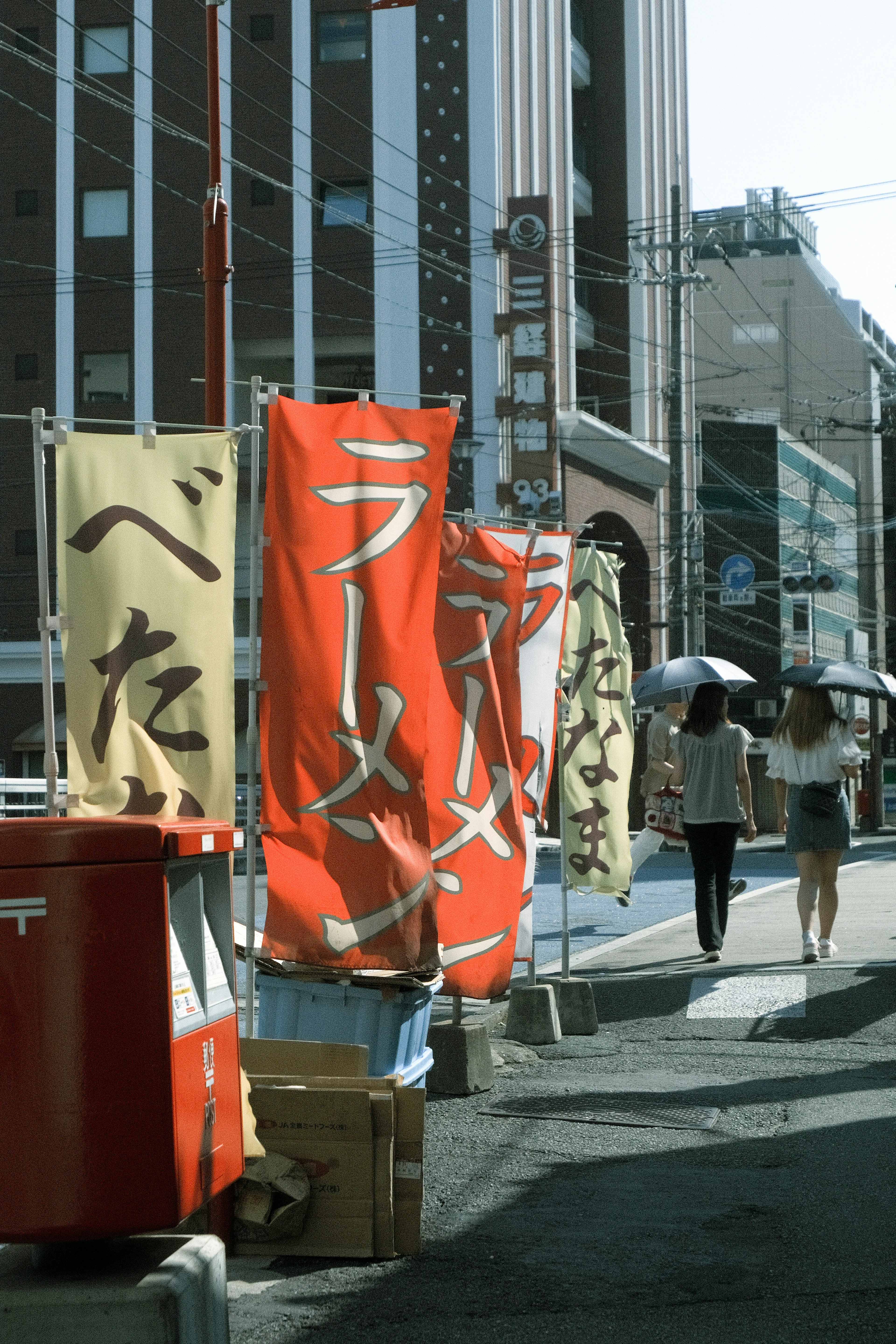 赤いラーメンの旗とカラフルな看板が並ぶ街の風景