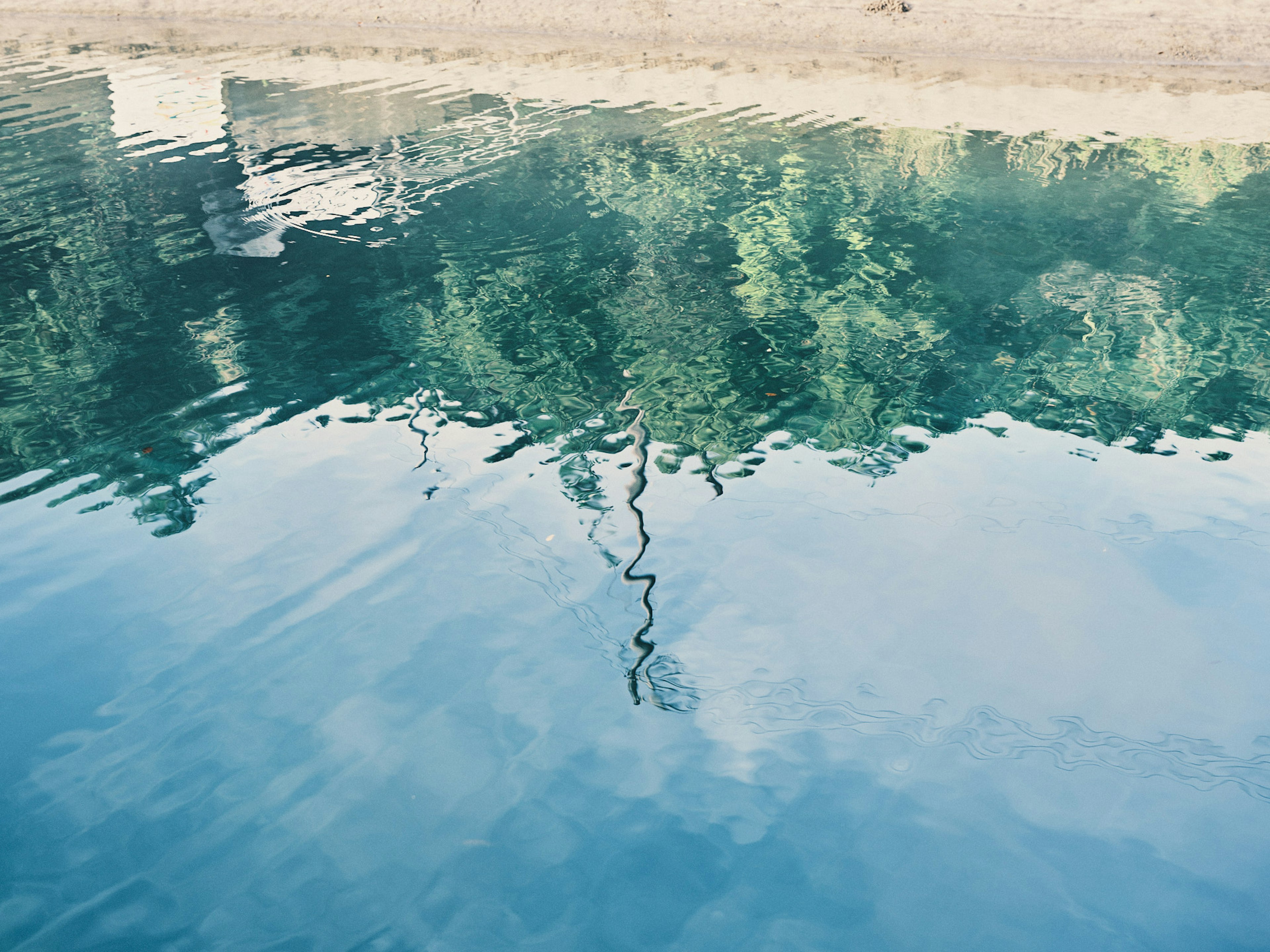 Refleksi dari pepohonan rimbun dan langit di permukaan air