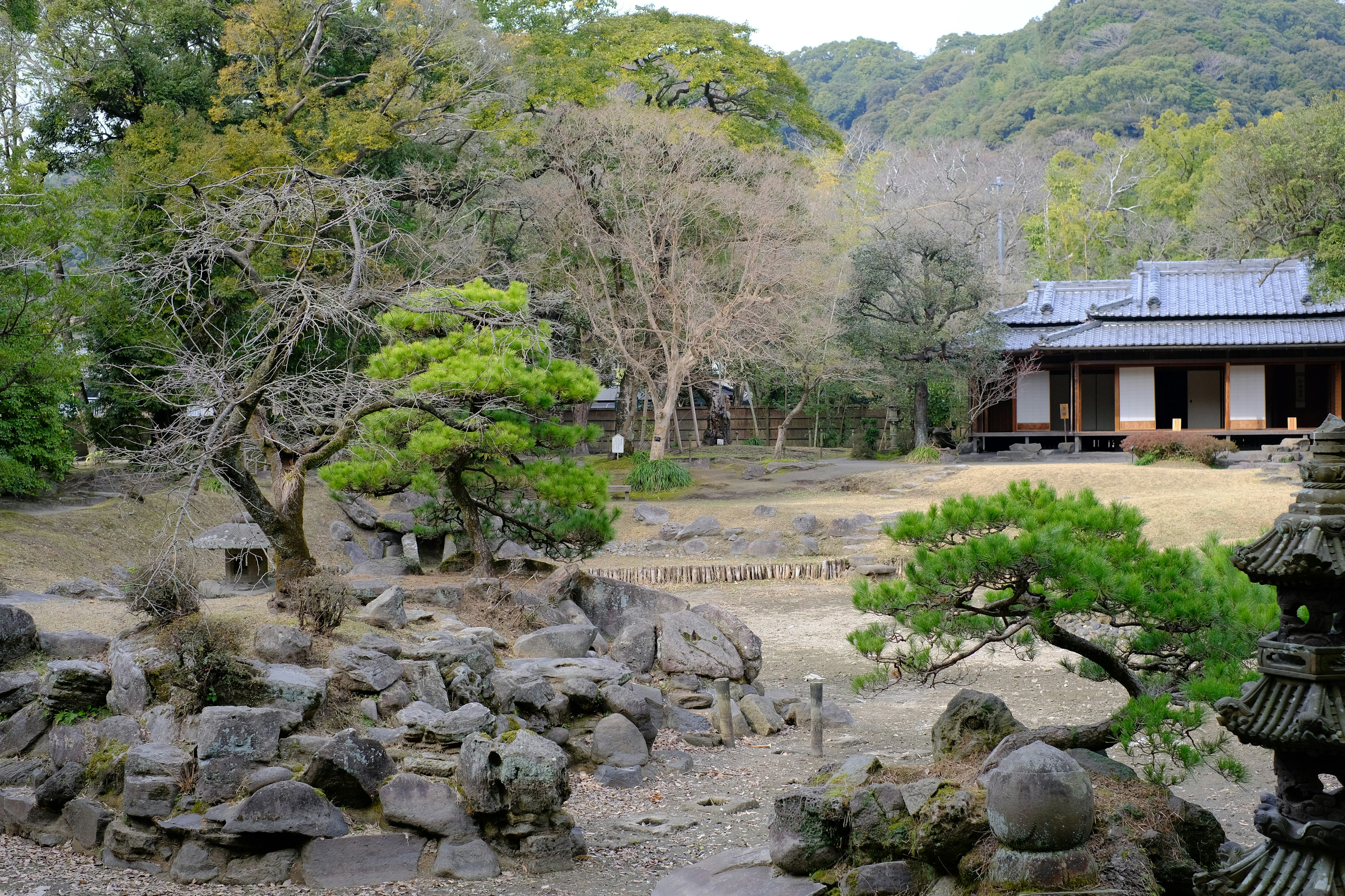 Pemandangan indah taman Jepang dengan batu dan pohon bangunan tradisional di latar belakang