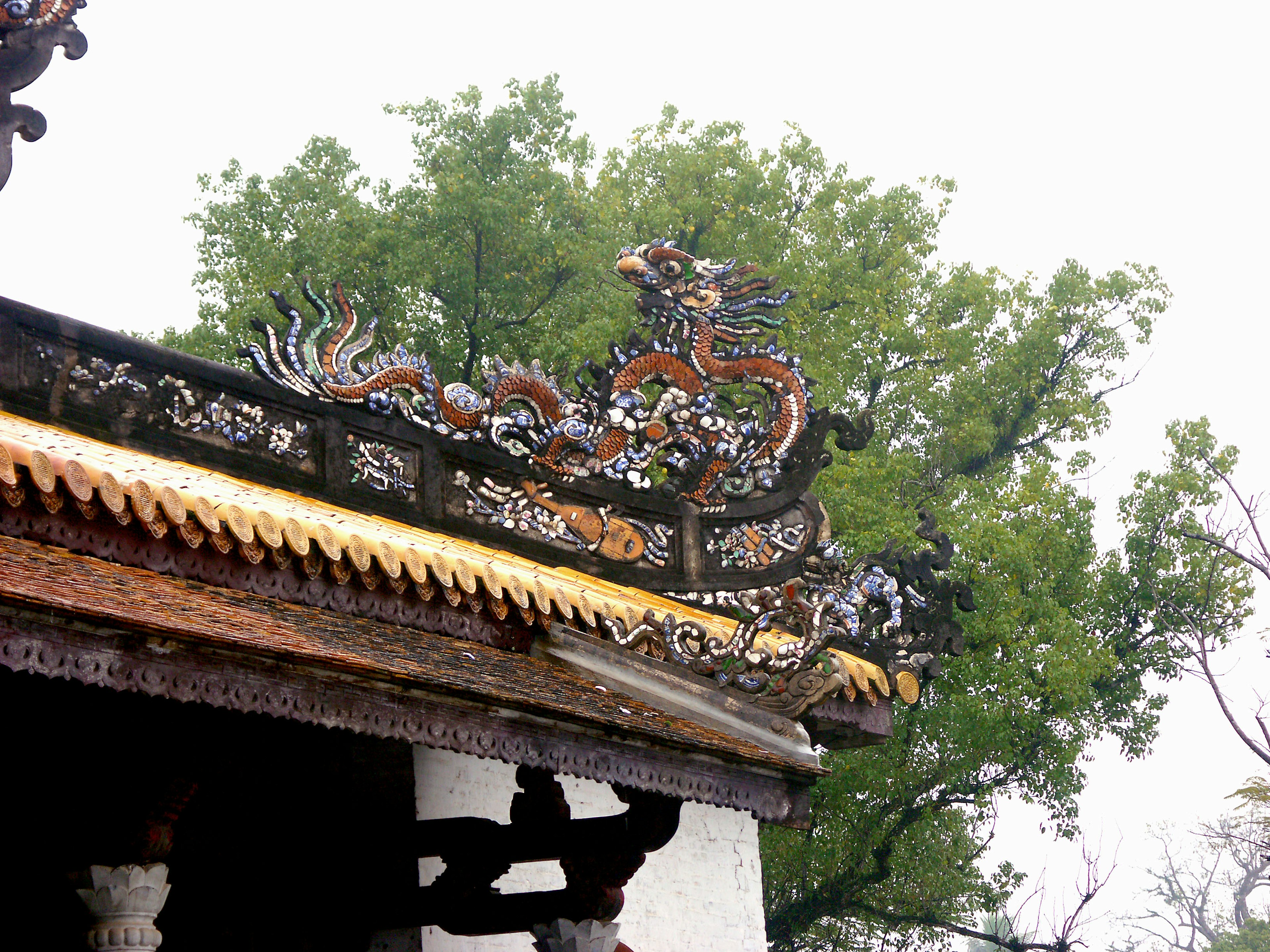 Dragon sculpture on the roof with green trees in the background