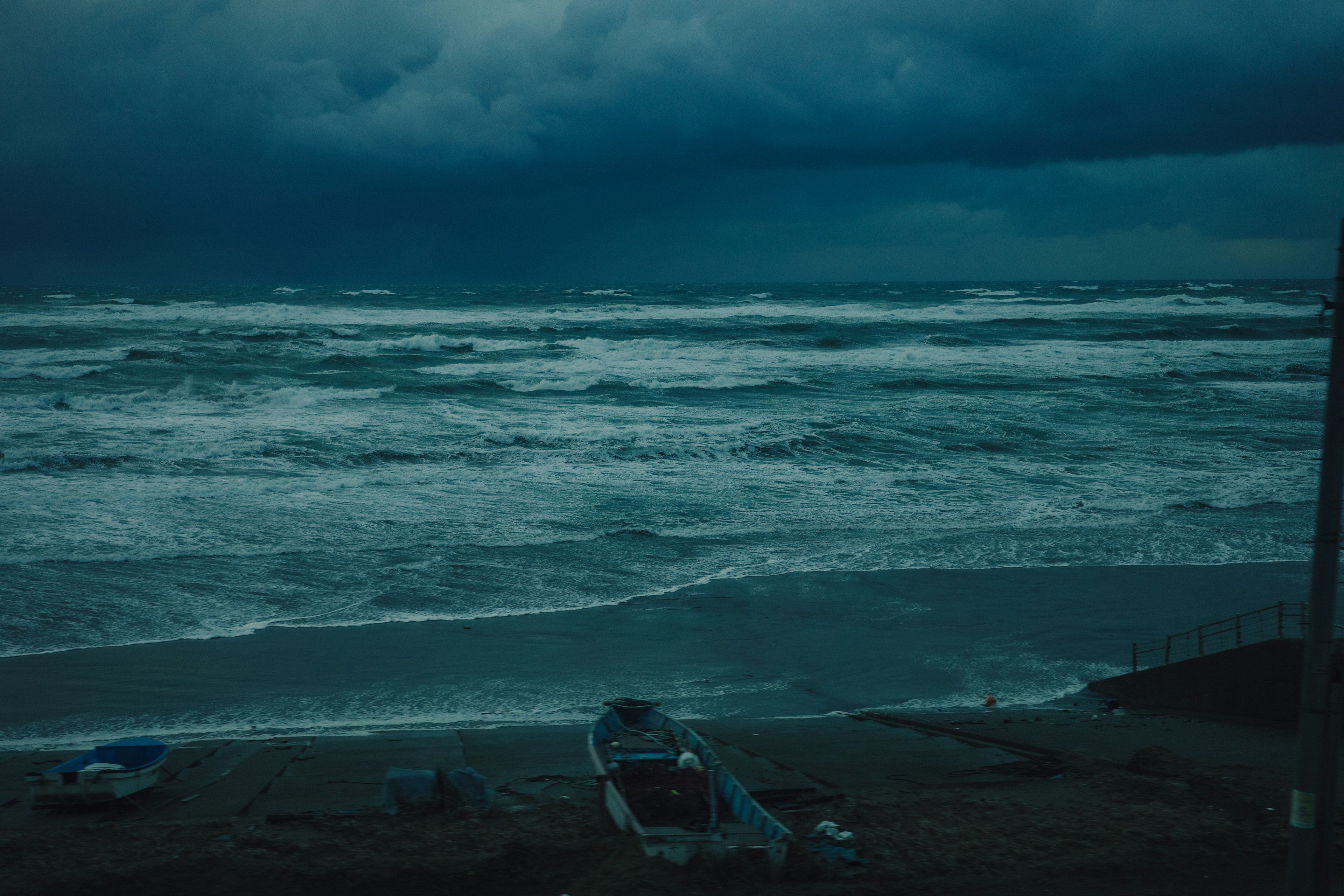 Stormy beach scene with dark waves and a boat on the shore