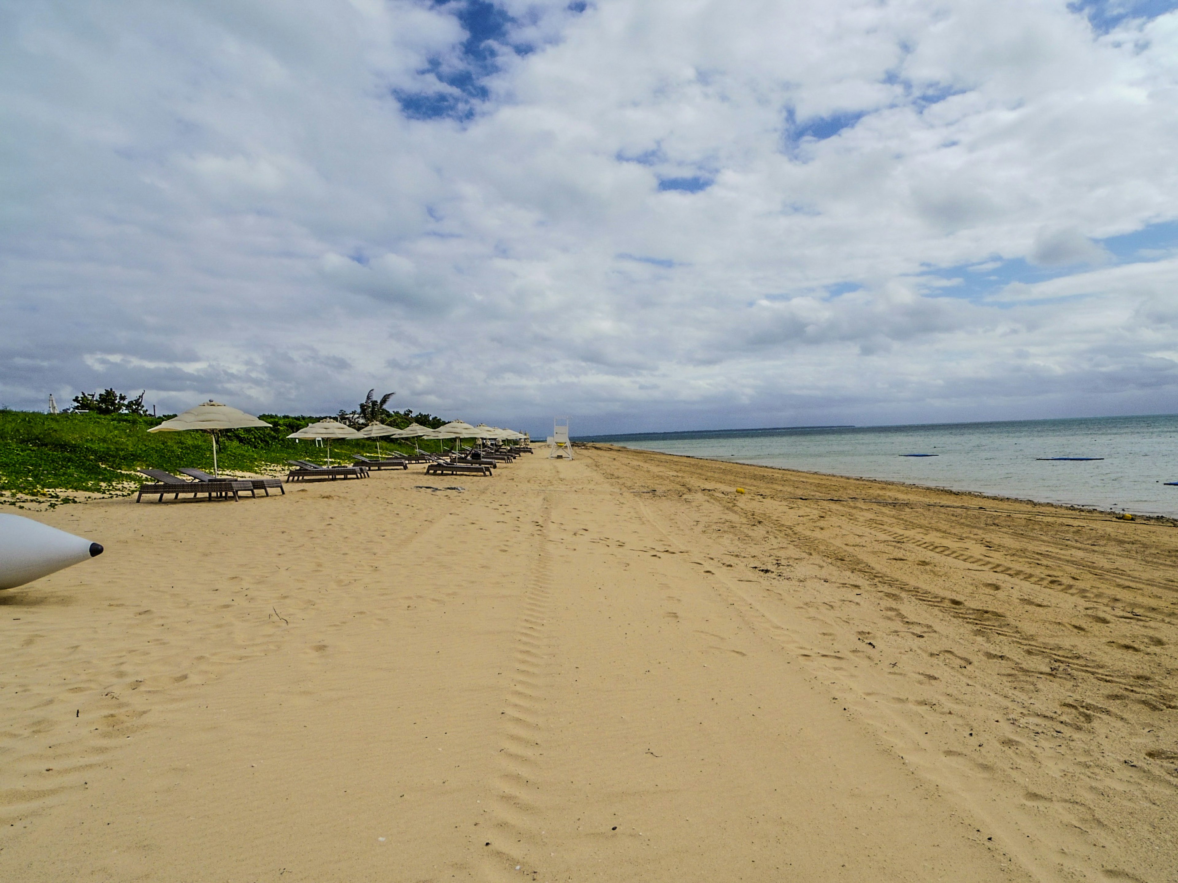 Sandstrand mit Blick auf den blauen Ozean Liegen und Sonnenschirme aufgereiht