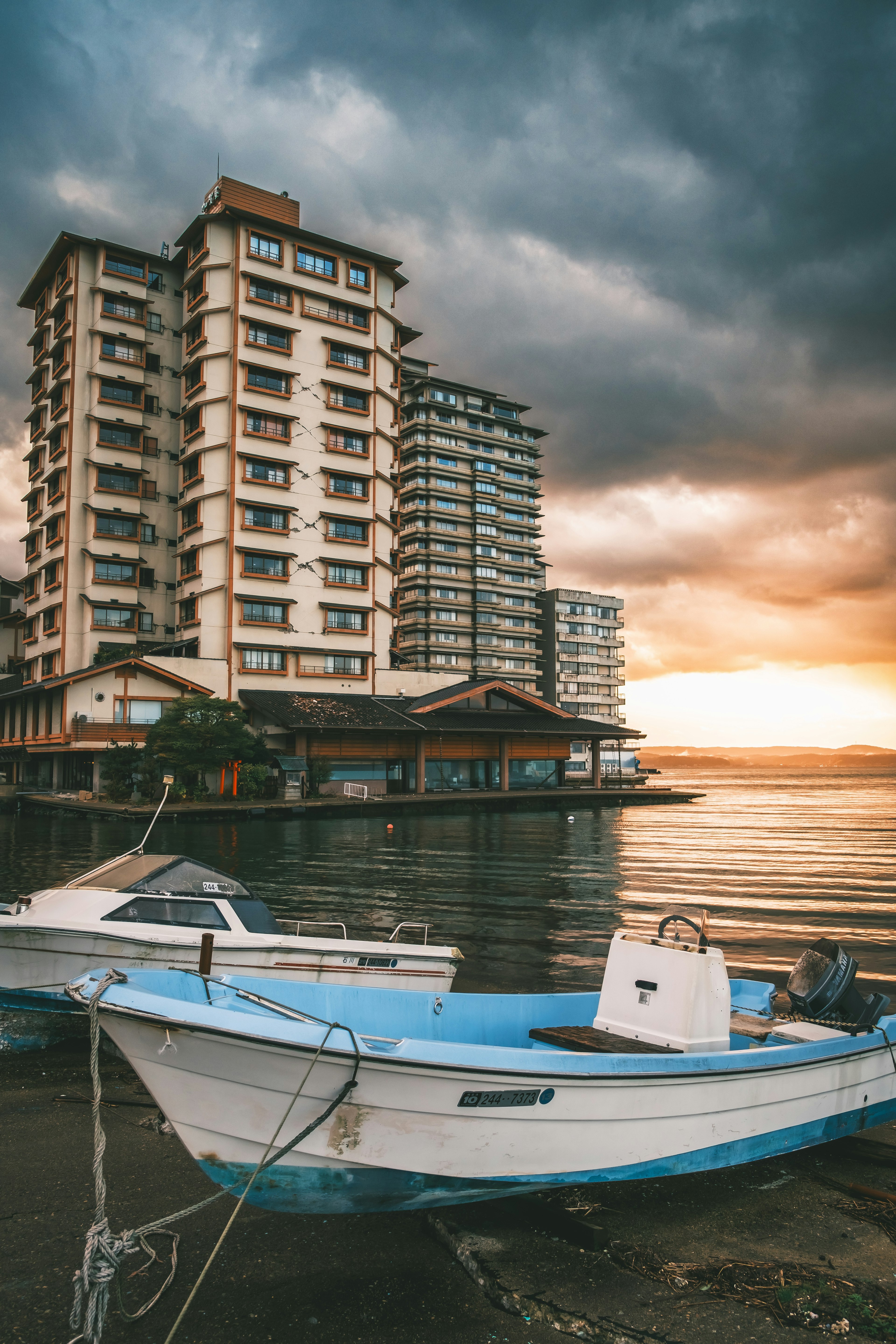 Pemandangan indah perahu di tepi laut dengan gedung tinggi saat matahari terbenam