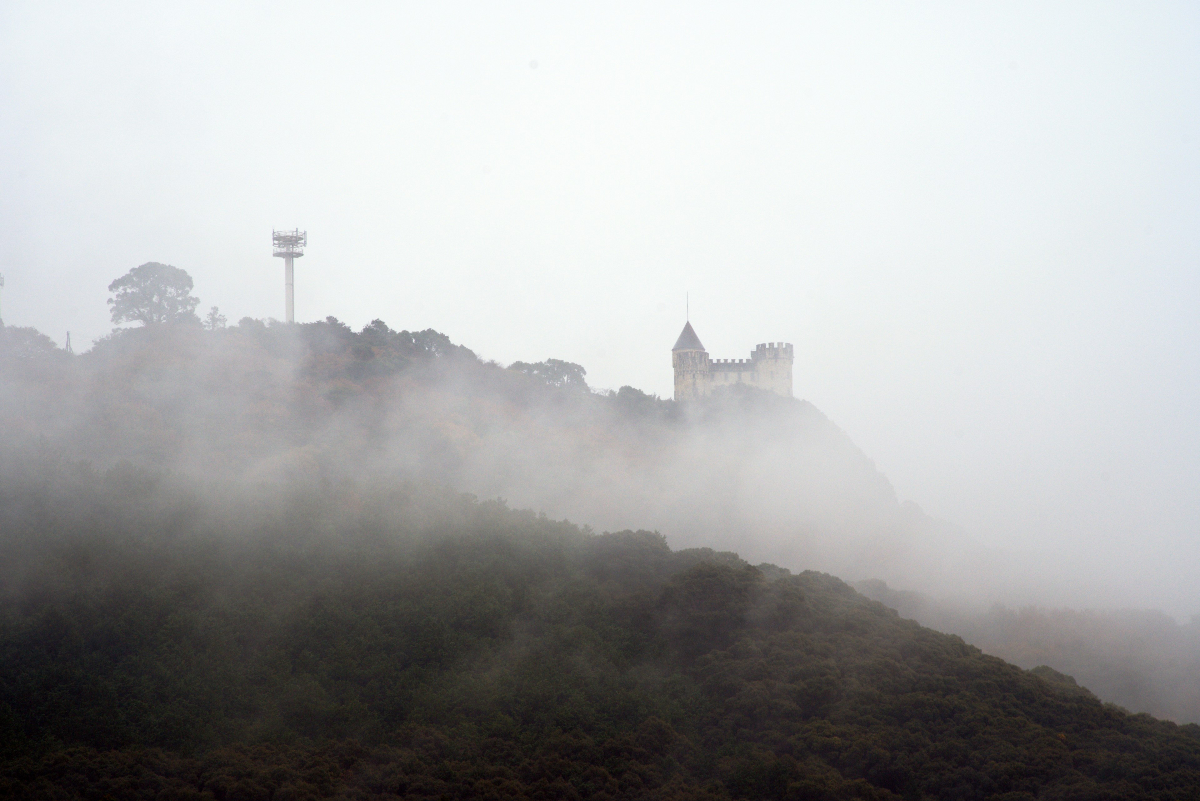 Altes Gebäude und Kommunikationsturm im Nebel auf einem Hügel