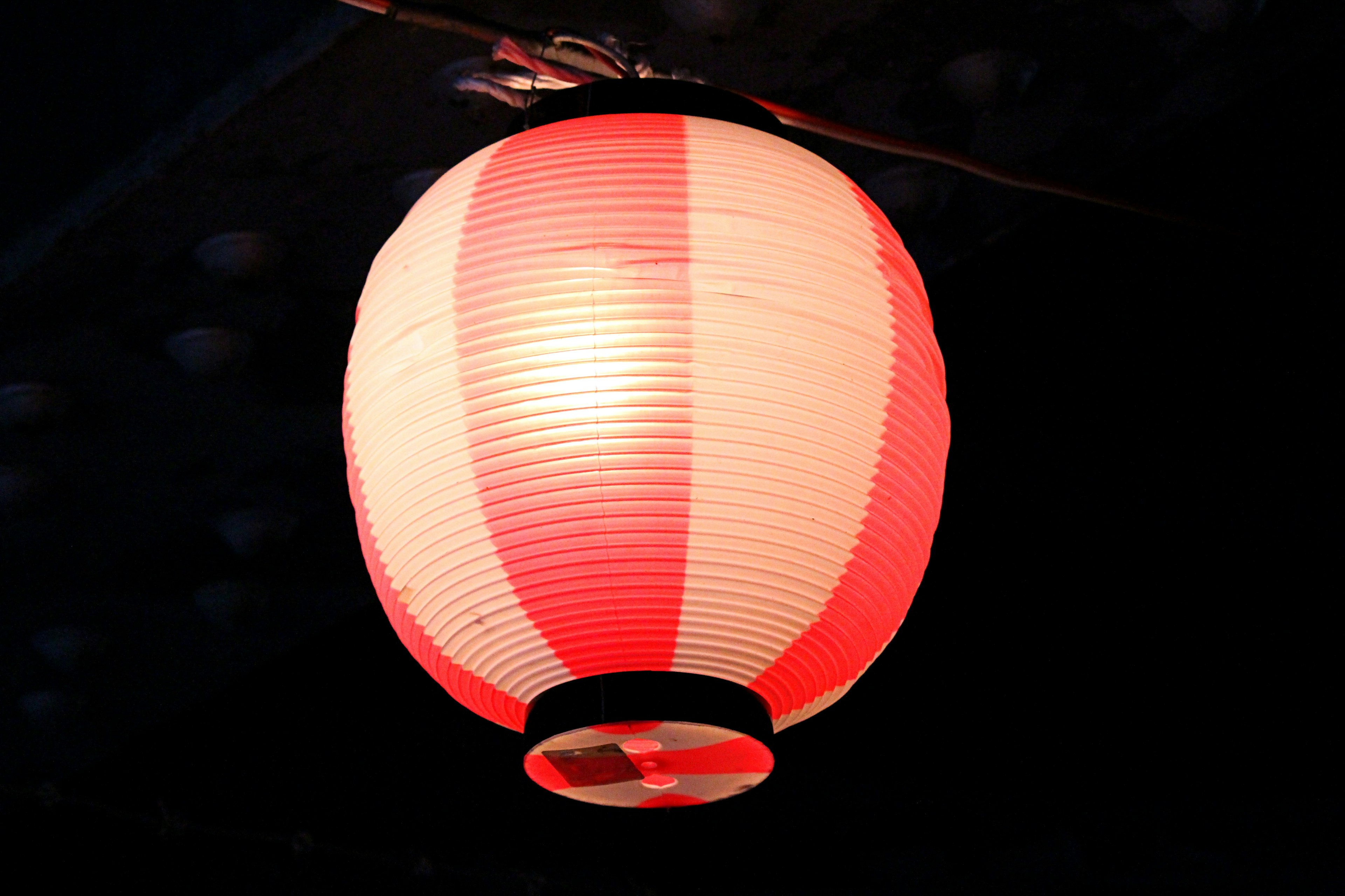 Red and white striped lantern glowing against a dark background