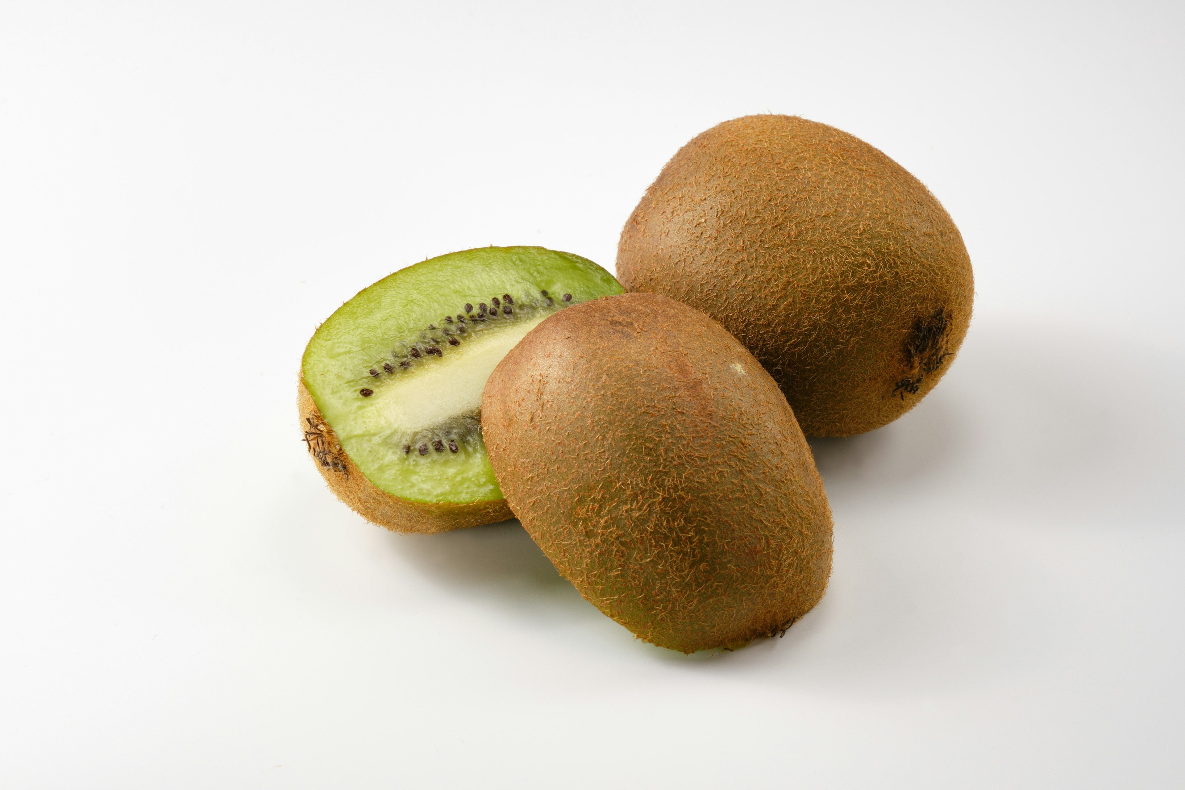 Whole and sliced kiwi fruit showing green flesh and brown skin