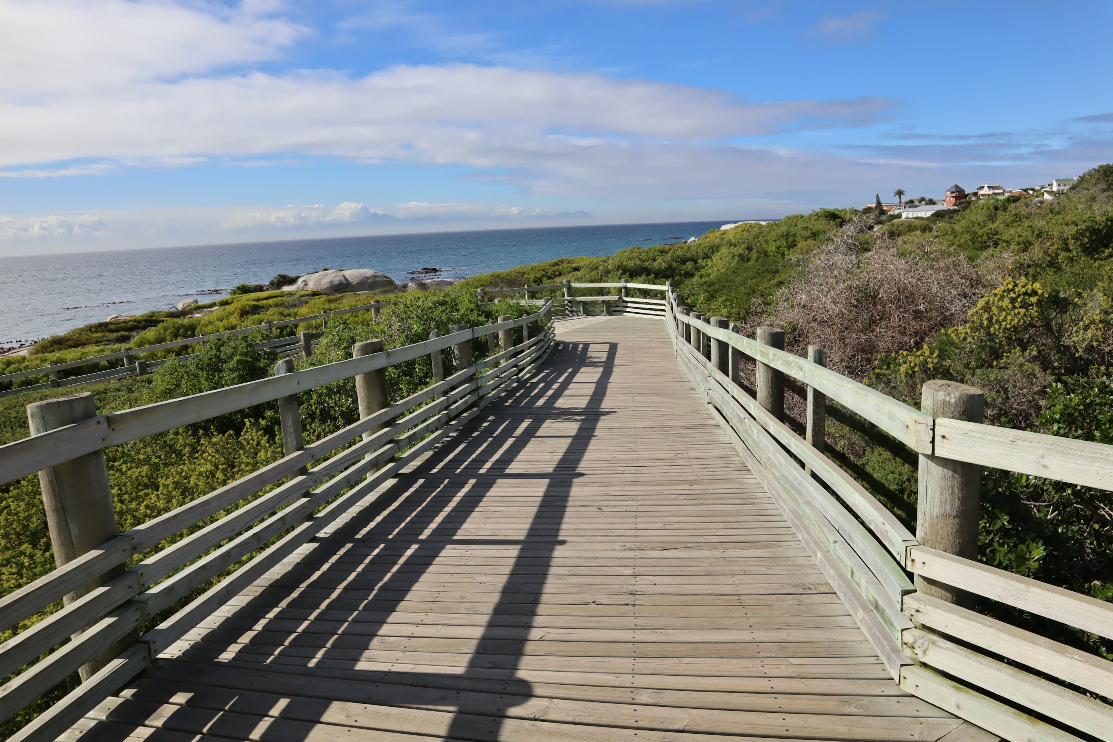 Wooden boardwalk leading to the sea with blue sky