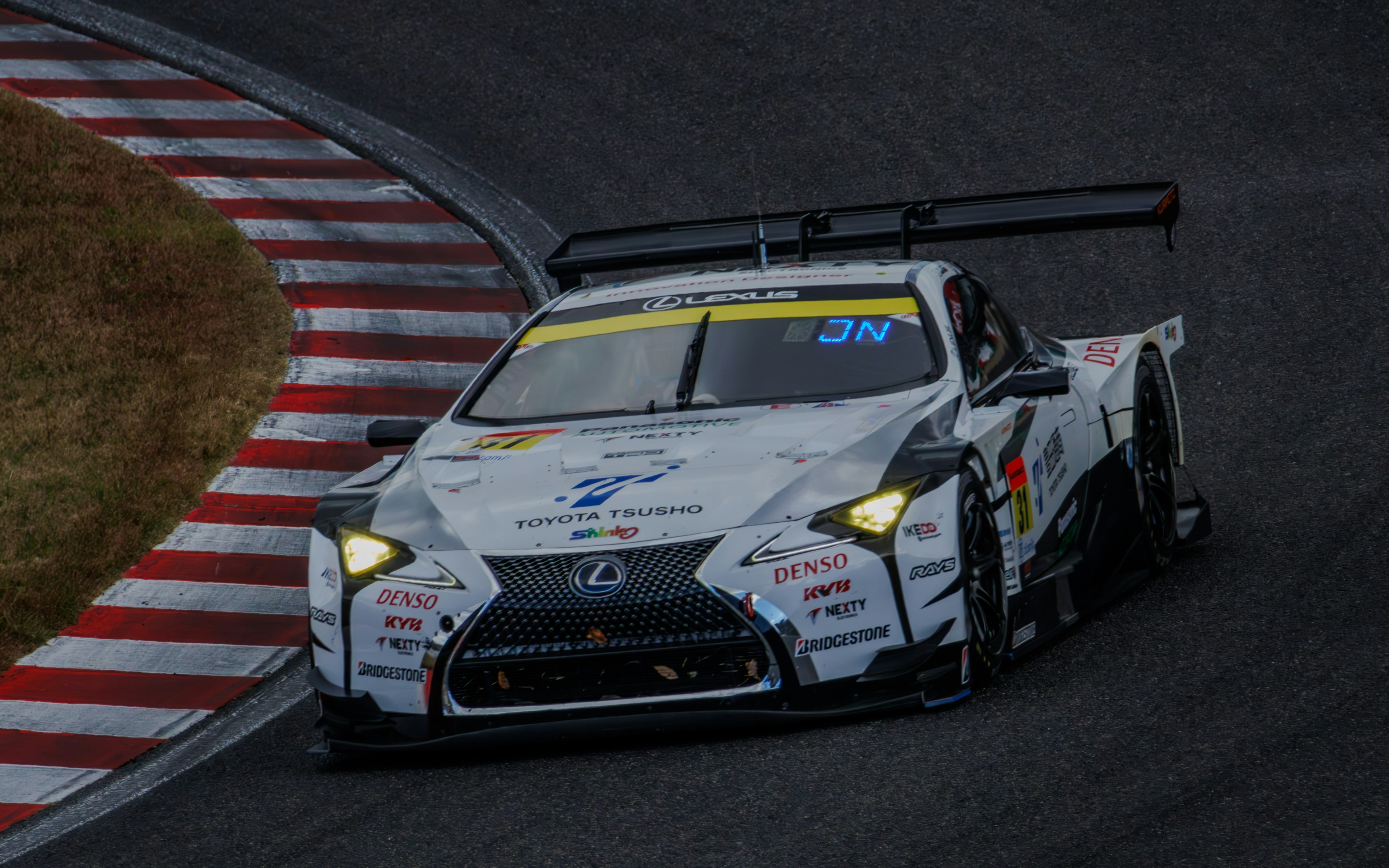 Coche de carreras blanco y negro navegando una curva en la pista