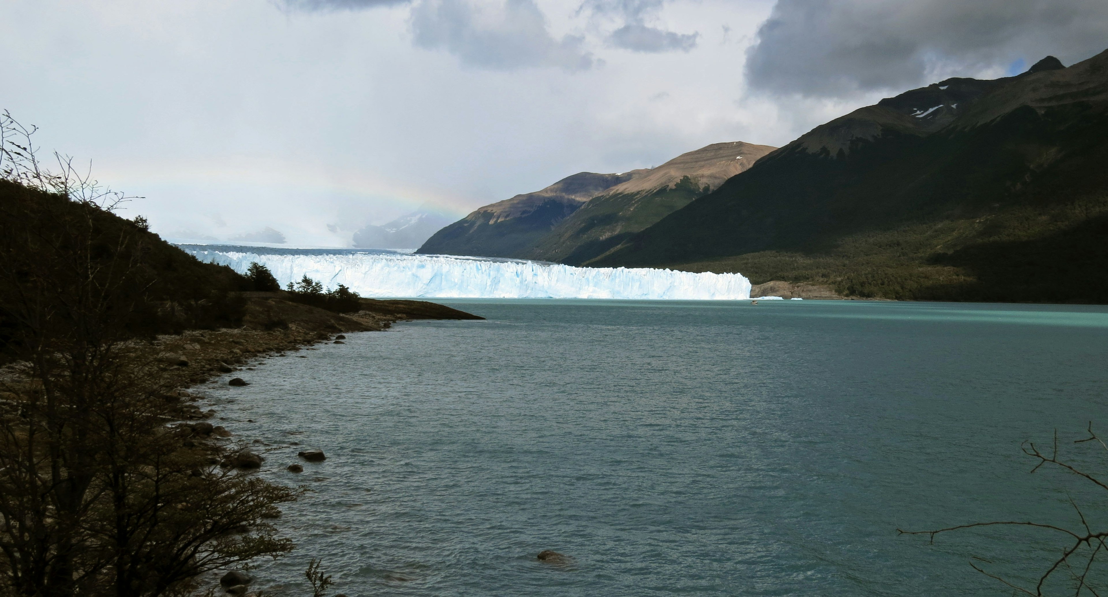 Vista escénica de un glaciar y un lago rodeado de montañas