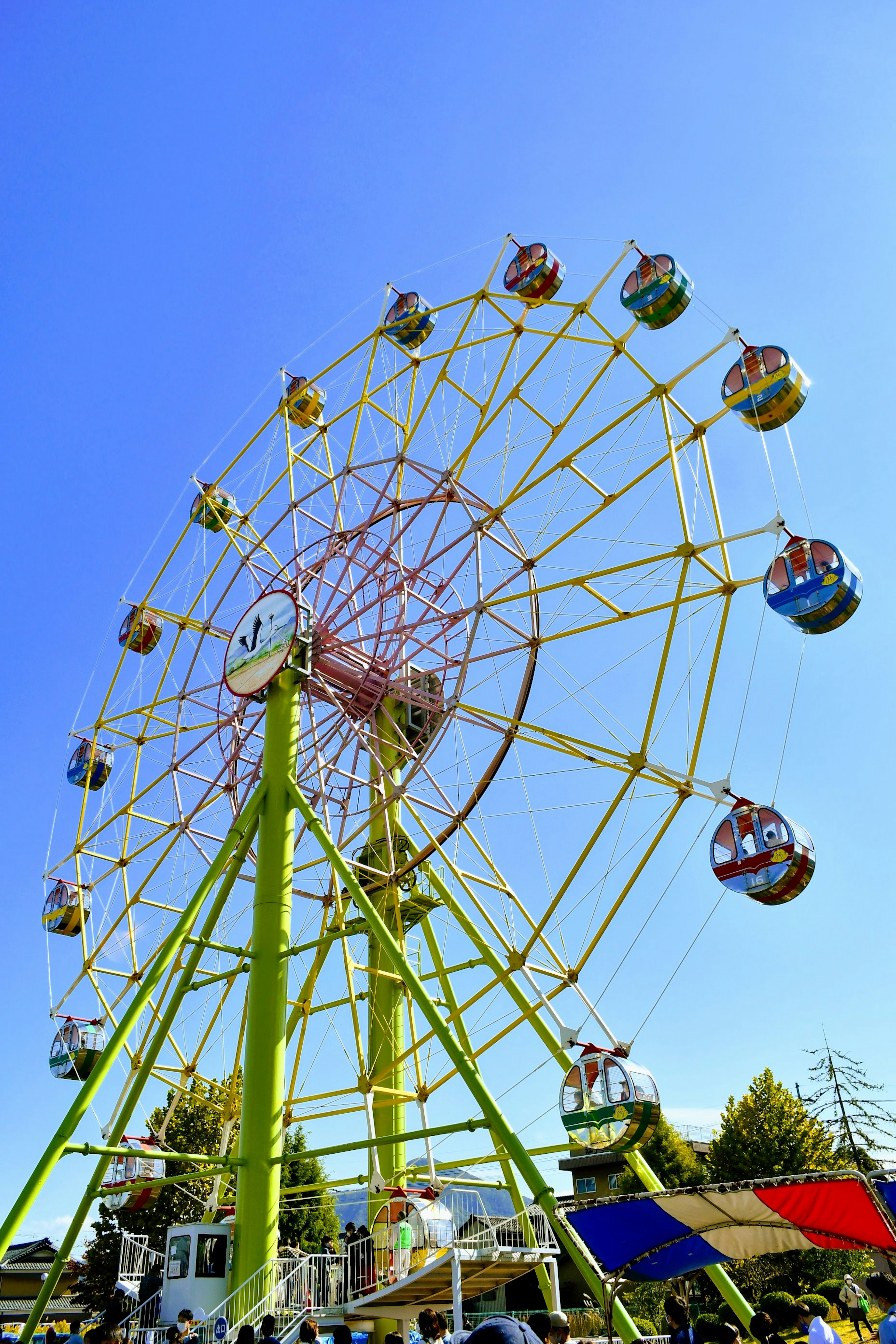 Une grande roue avec des gondoles colorées sous un ciel bleu clair