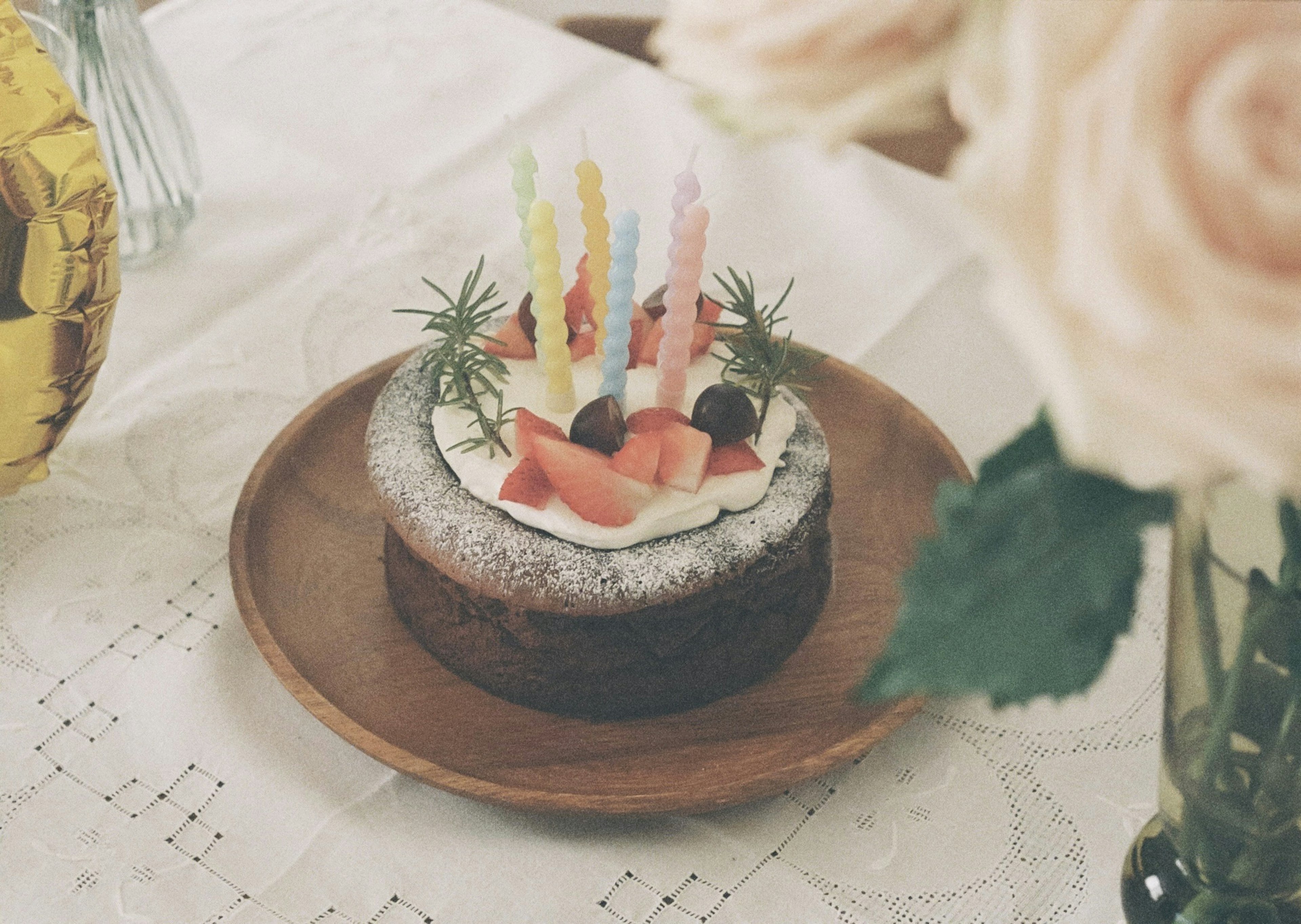 Kue ulang tahun dengan lilin berwarna-warni dan hiasan buah