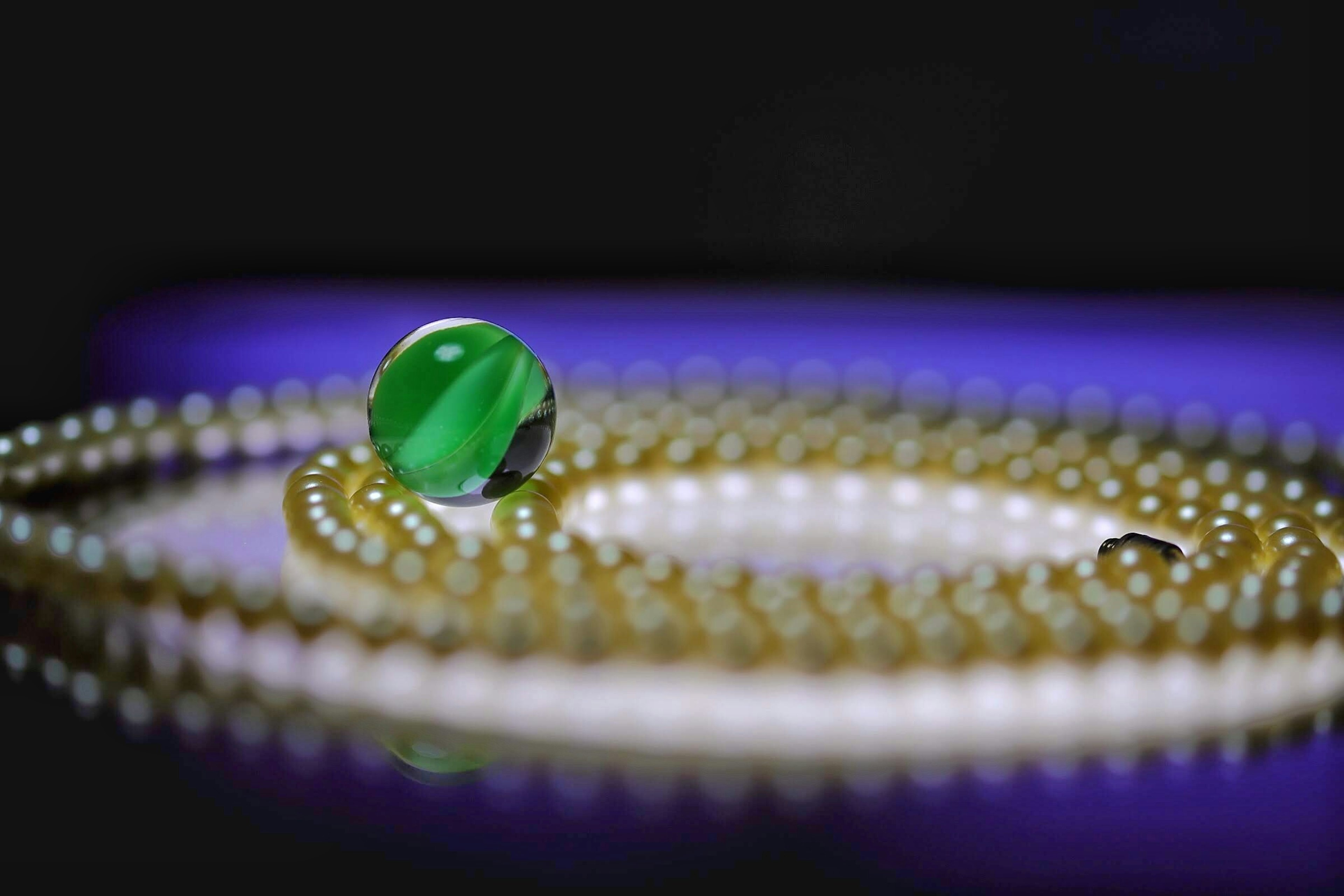 Green marble with pearl necklace on a dark background