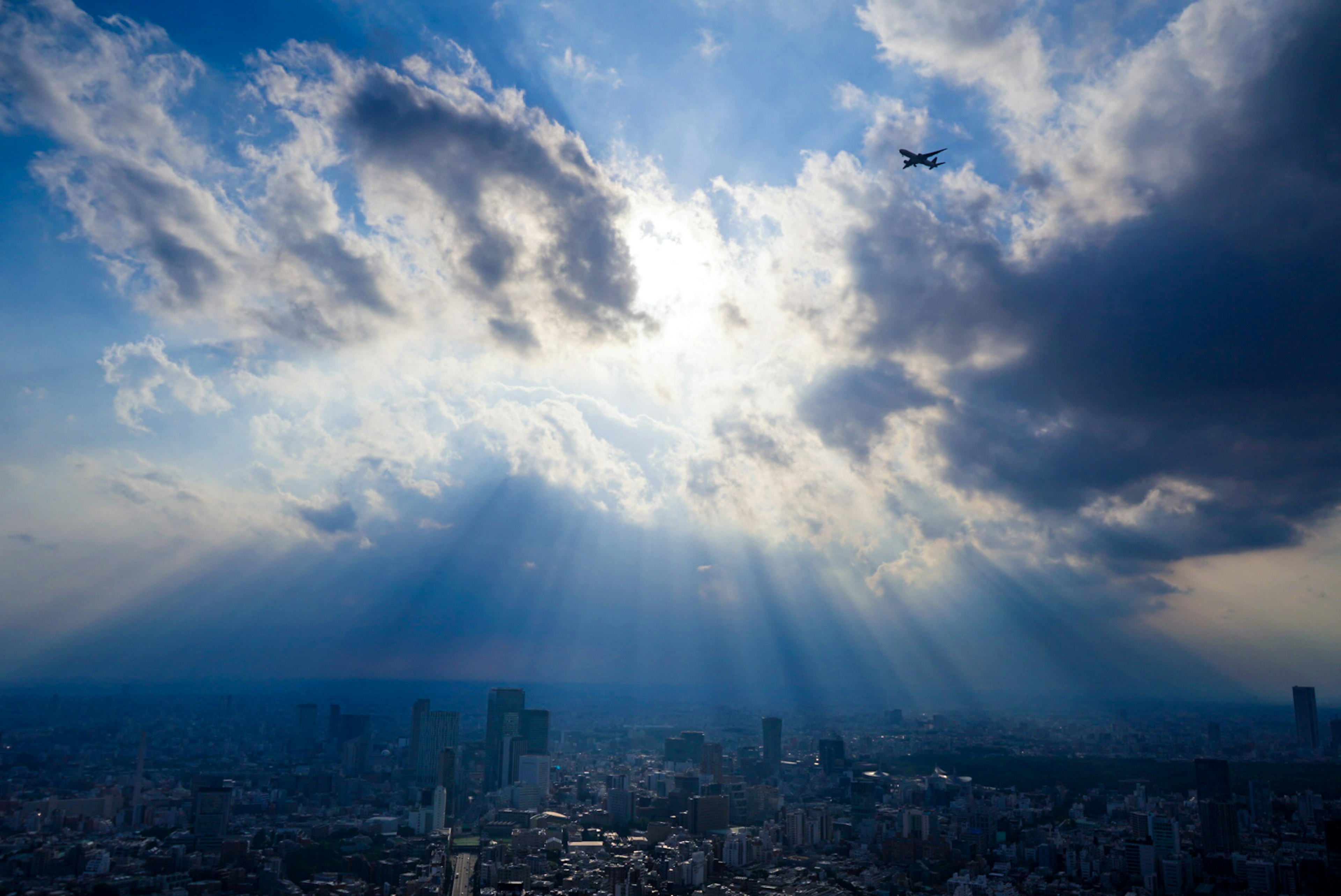 都市の上空に広がる青空と雲の光のビーム