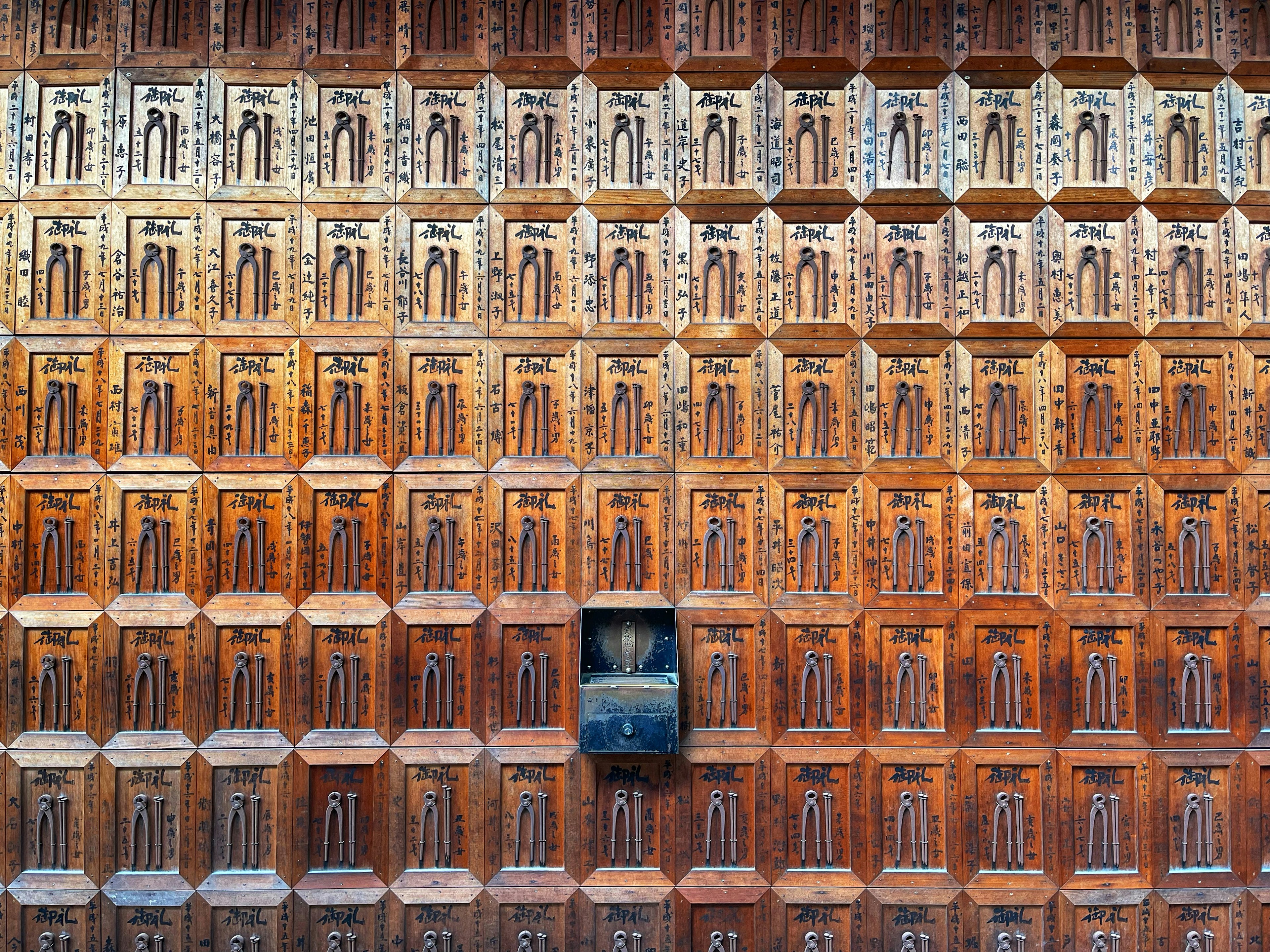 Decorative wooden wall with intricate patterns and a black box in the center