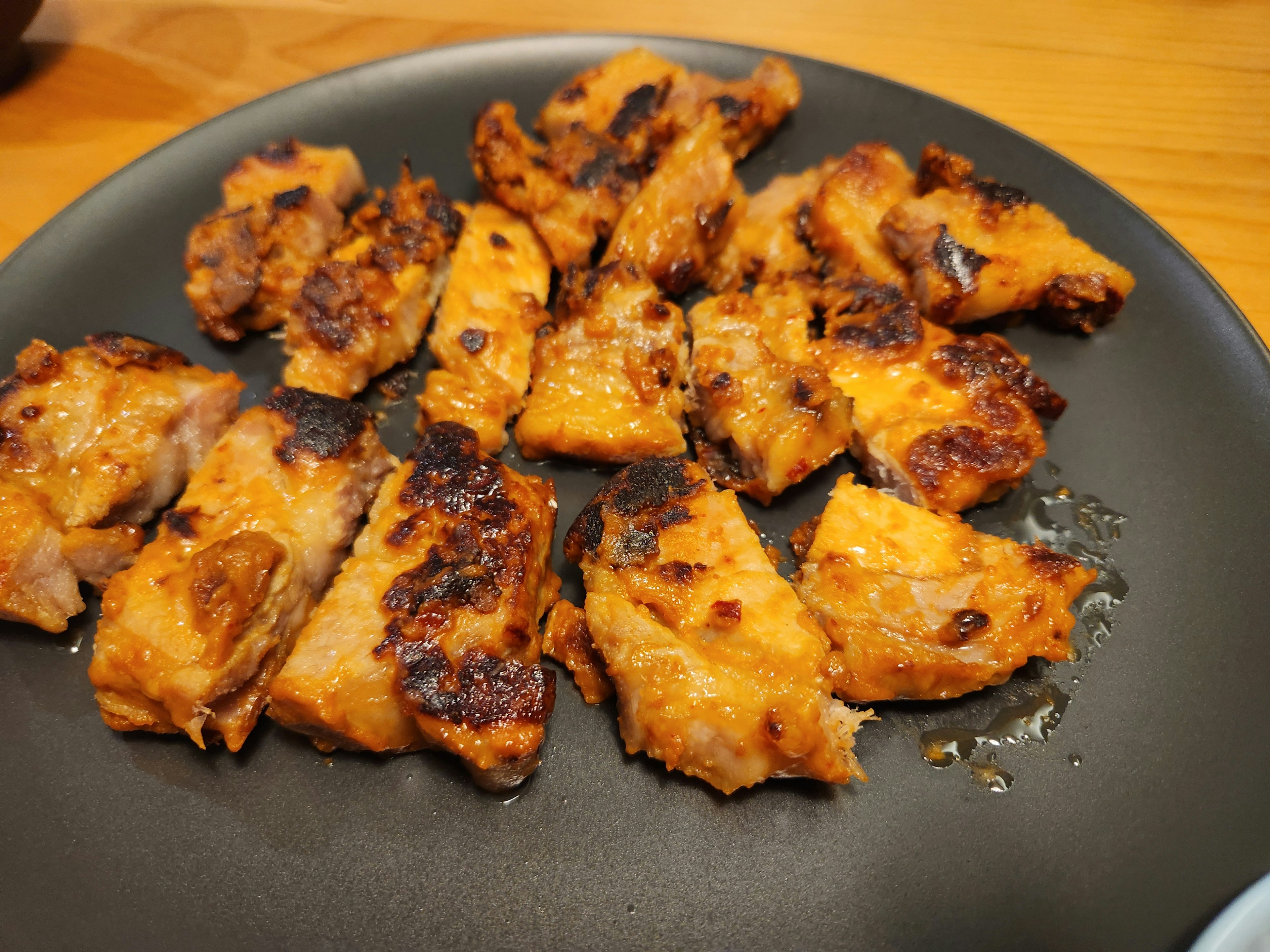 Plate of grilled chicken pieces arranged on a black dish