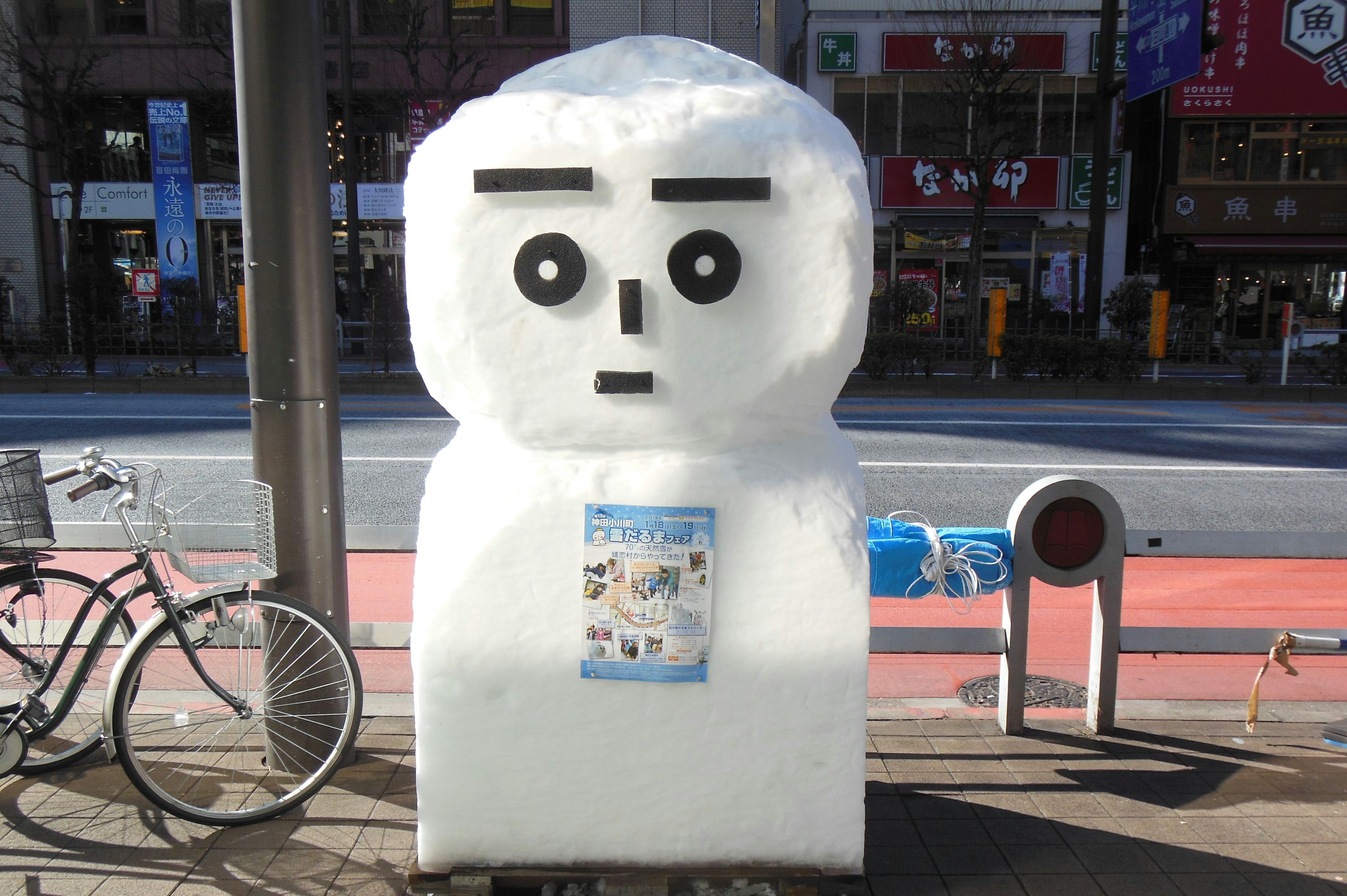 A snow figure resembling a humanoid stands on the street