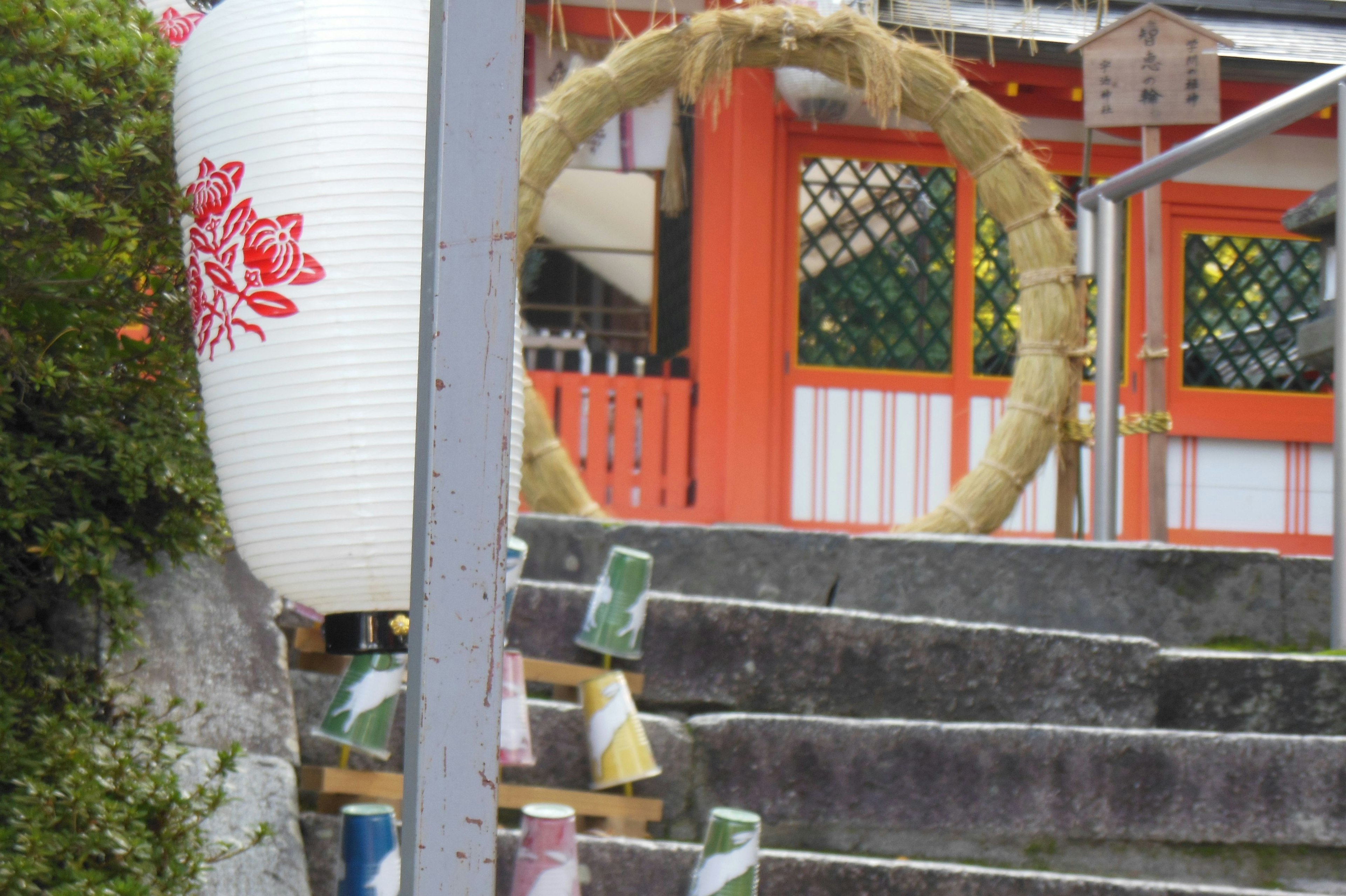 Stairway scene of a shrine with a red building and a lantern