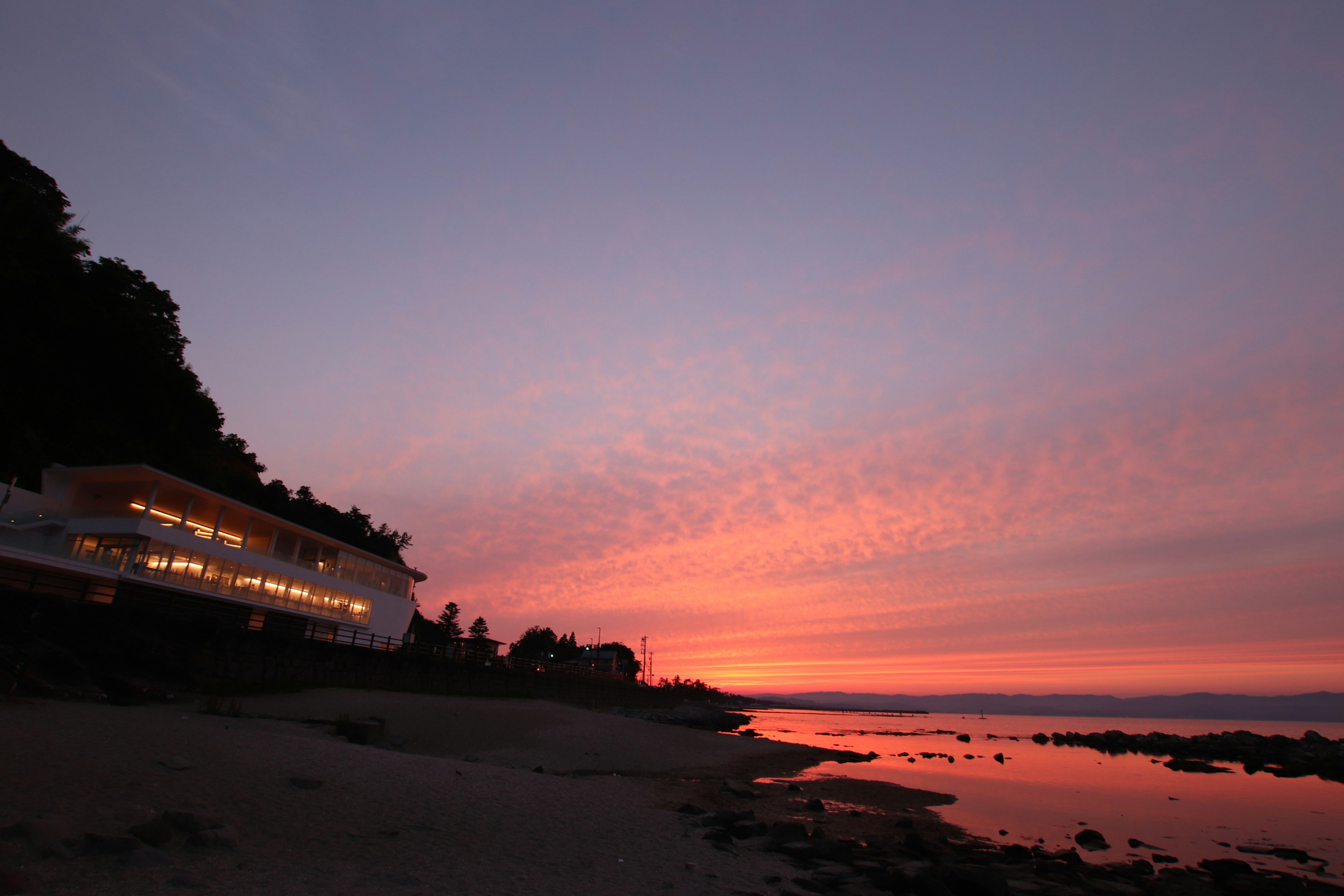 Bâtiment blanc sur une plage au coucher du soleil avec des couleurs de ciel vibrantes