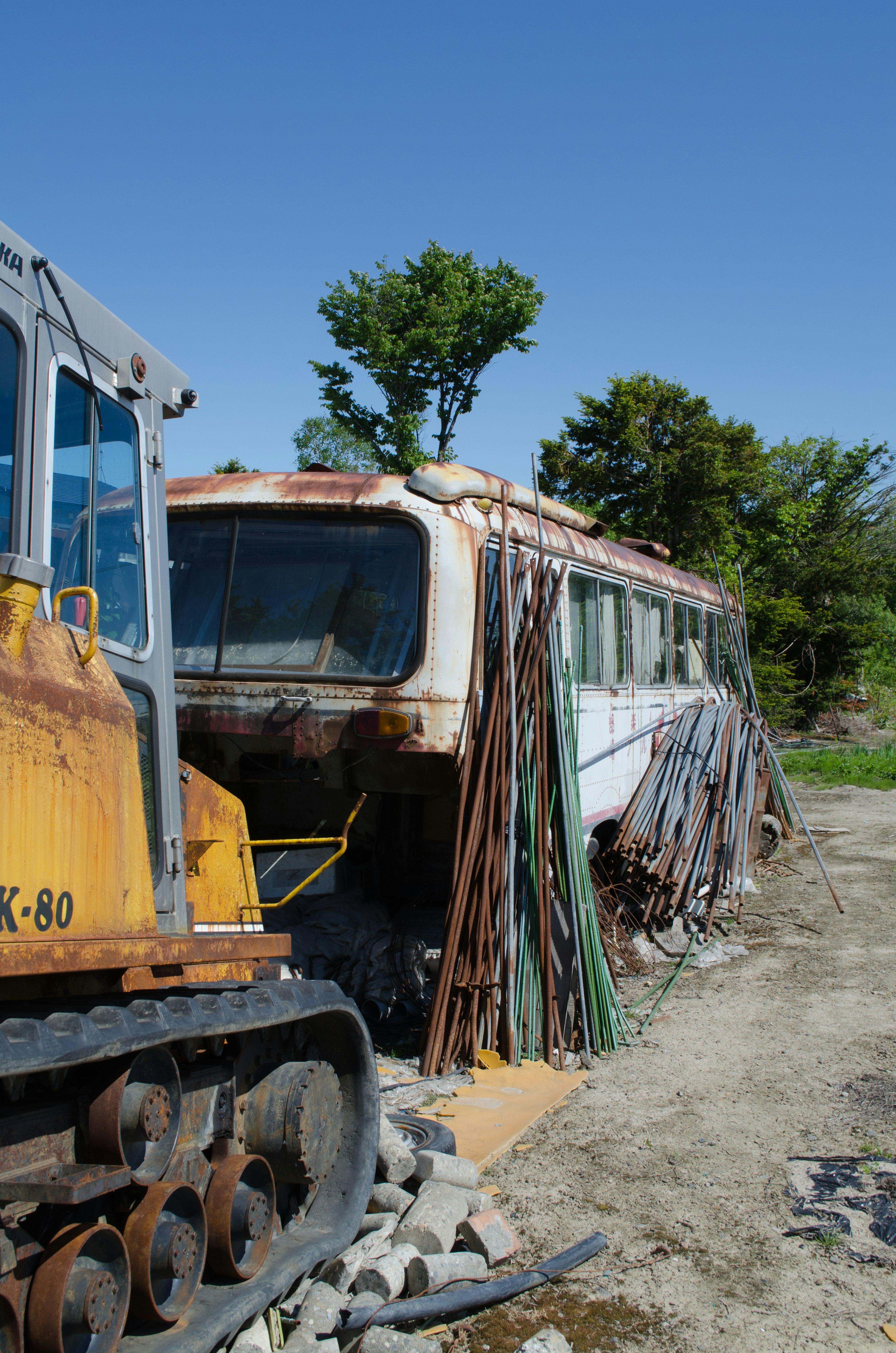 Abandoned bus with rusted exterior alongside construction equipment