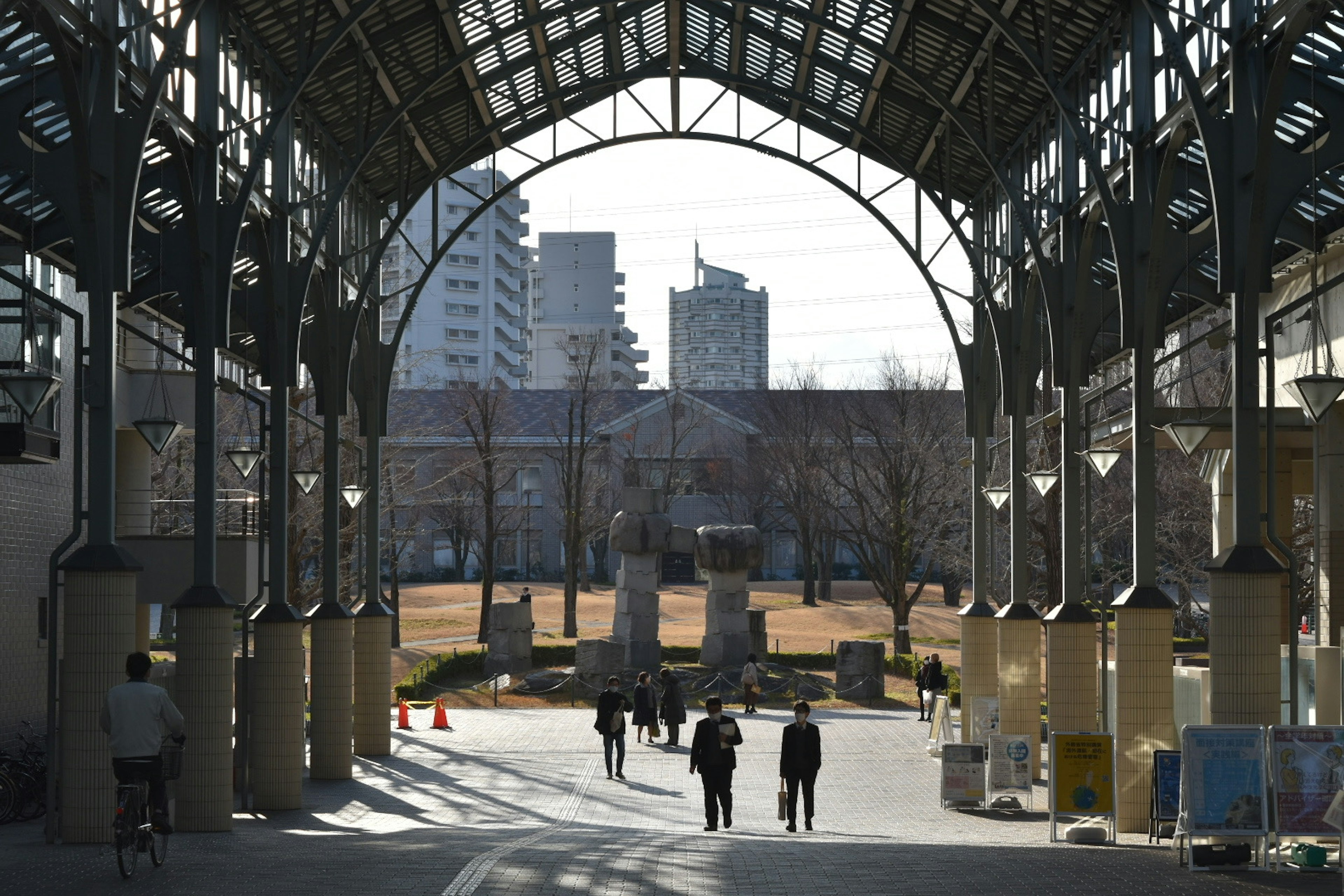 アーチ型の屋根の下に歩く人々と背景のビル群