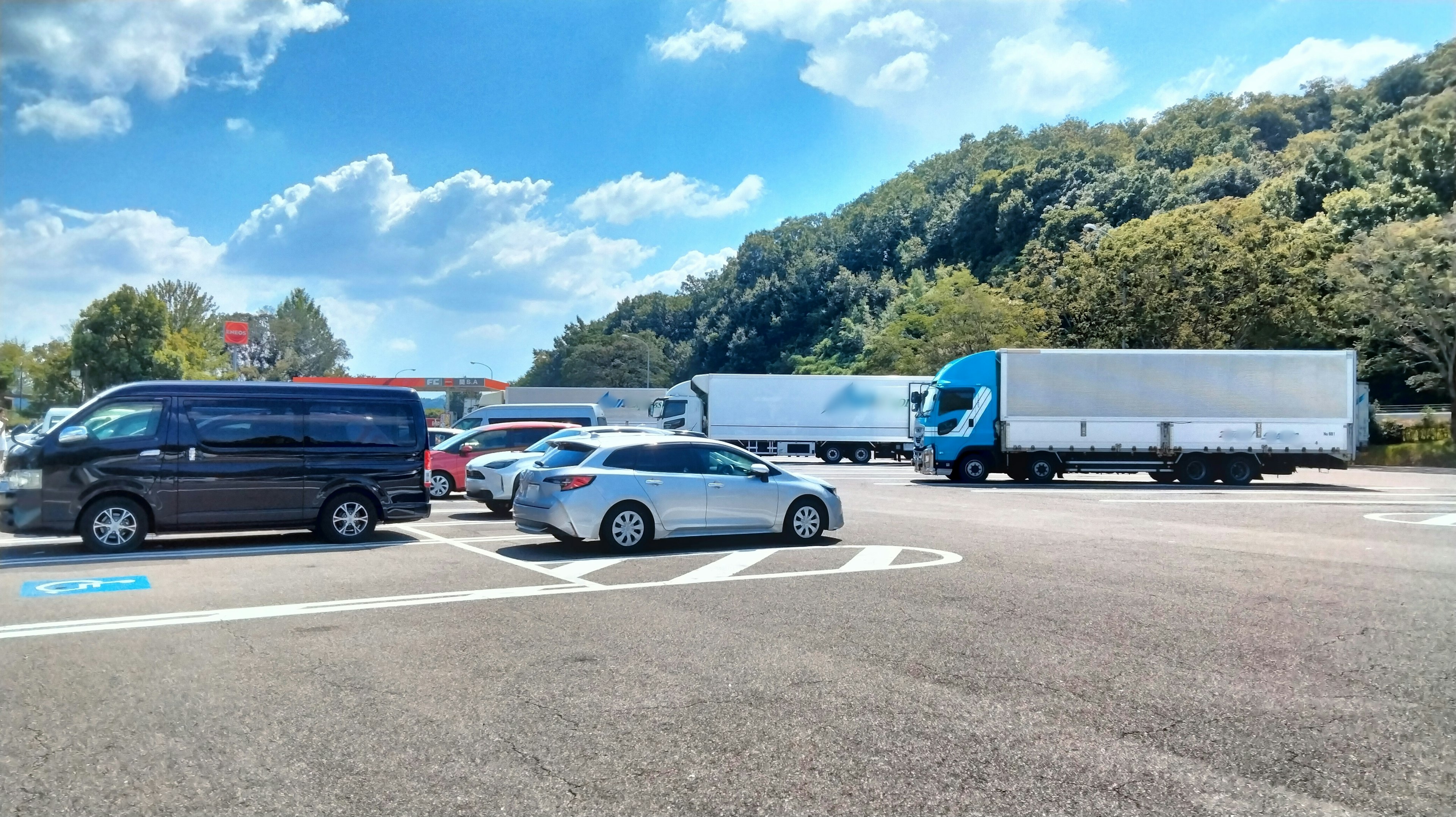 Parking lot scene with cars and trucks under a blue sky