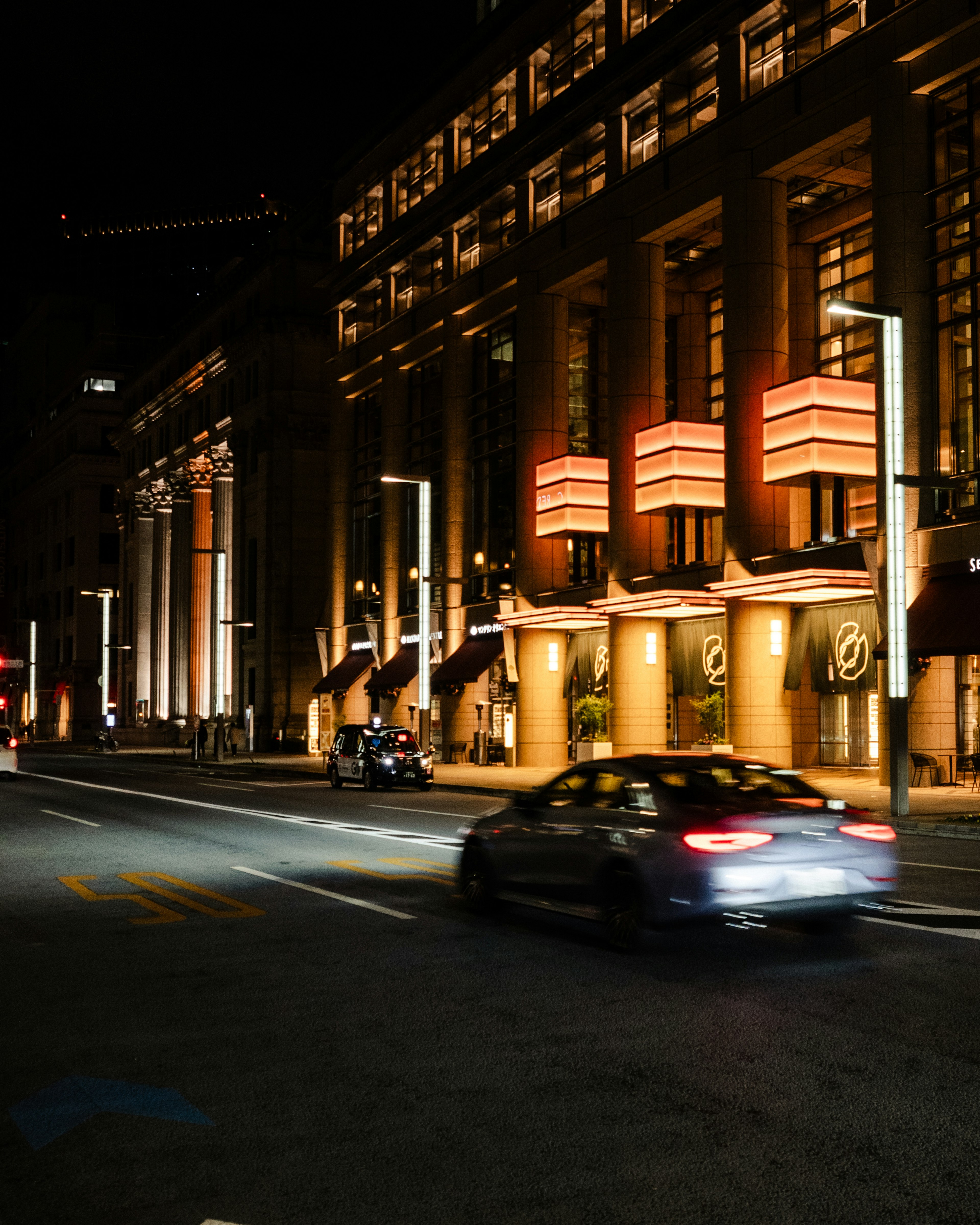 Voiture passant devant des bâtiments illuminés la nuit dans un cadre urbain