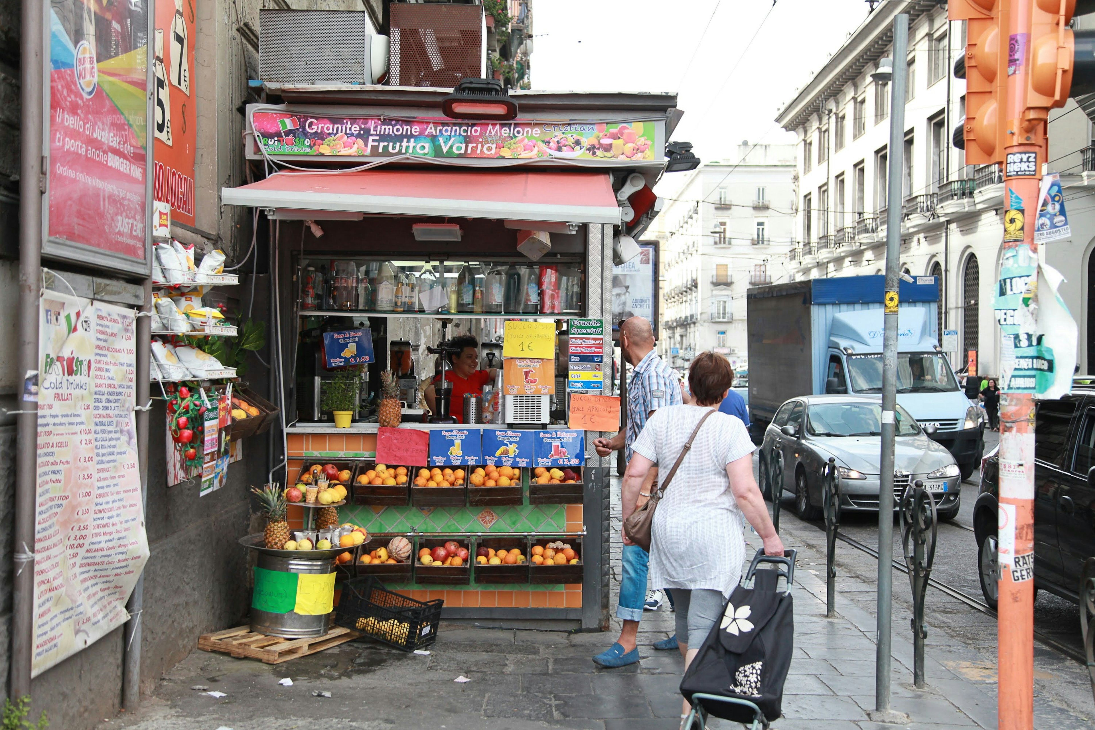 Puesto de frutas en la calle con un transeúnte