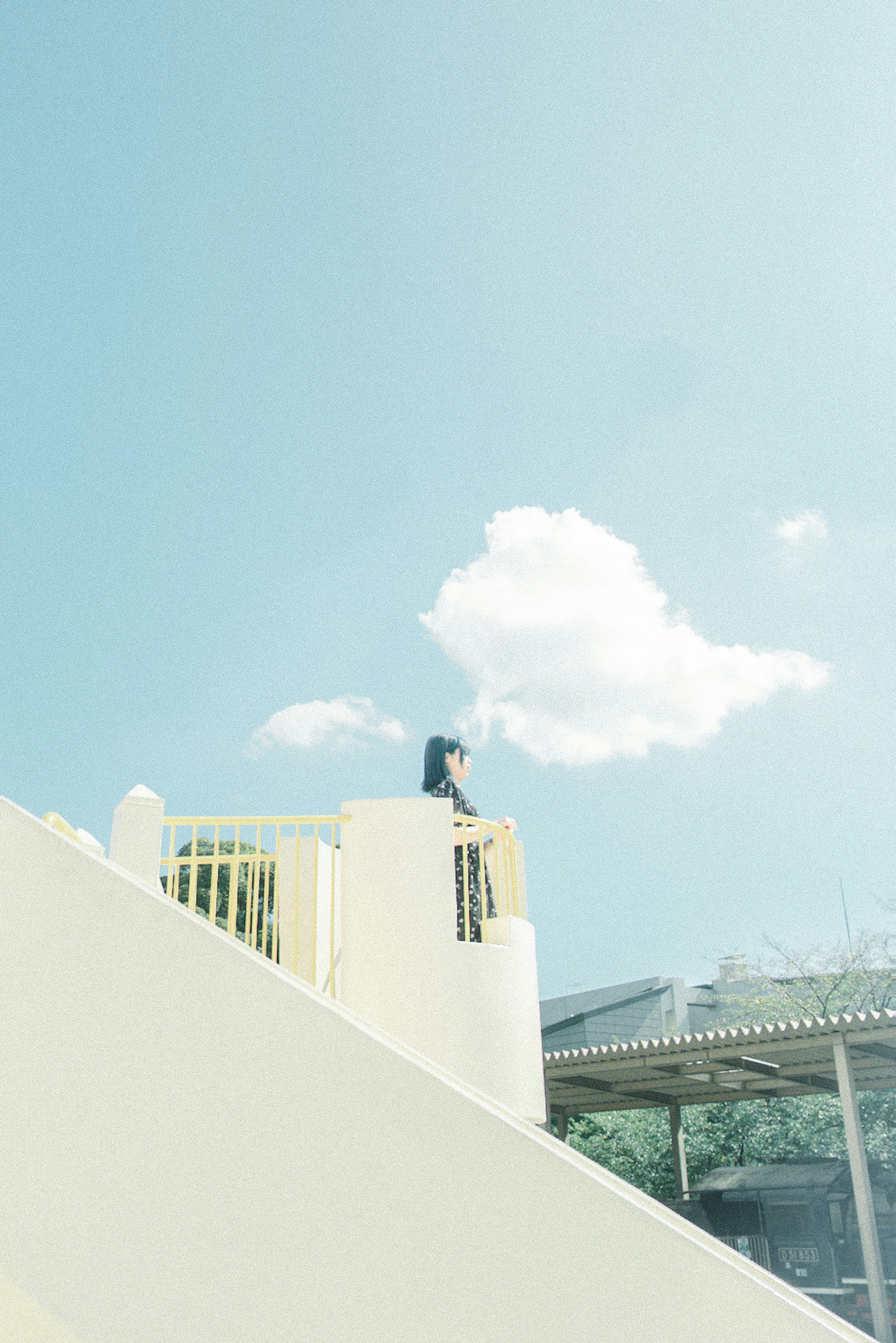 Eine Frau steht auf Treppen unter einem blauen Himmel mit weißen Wolken