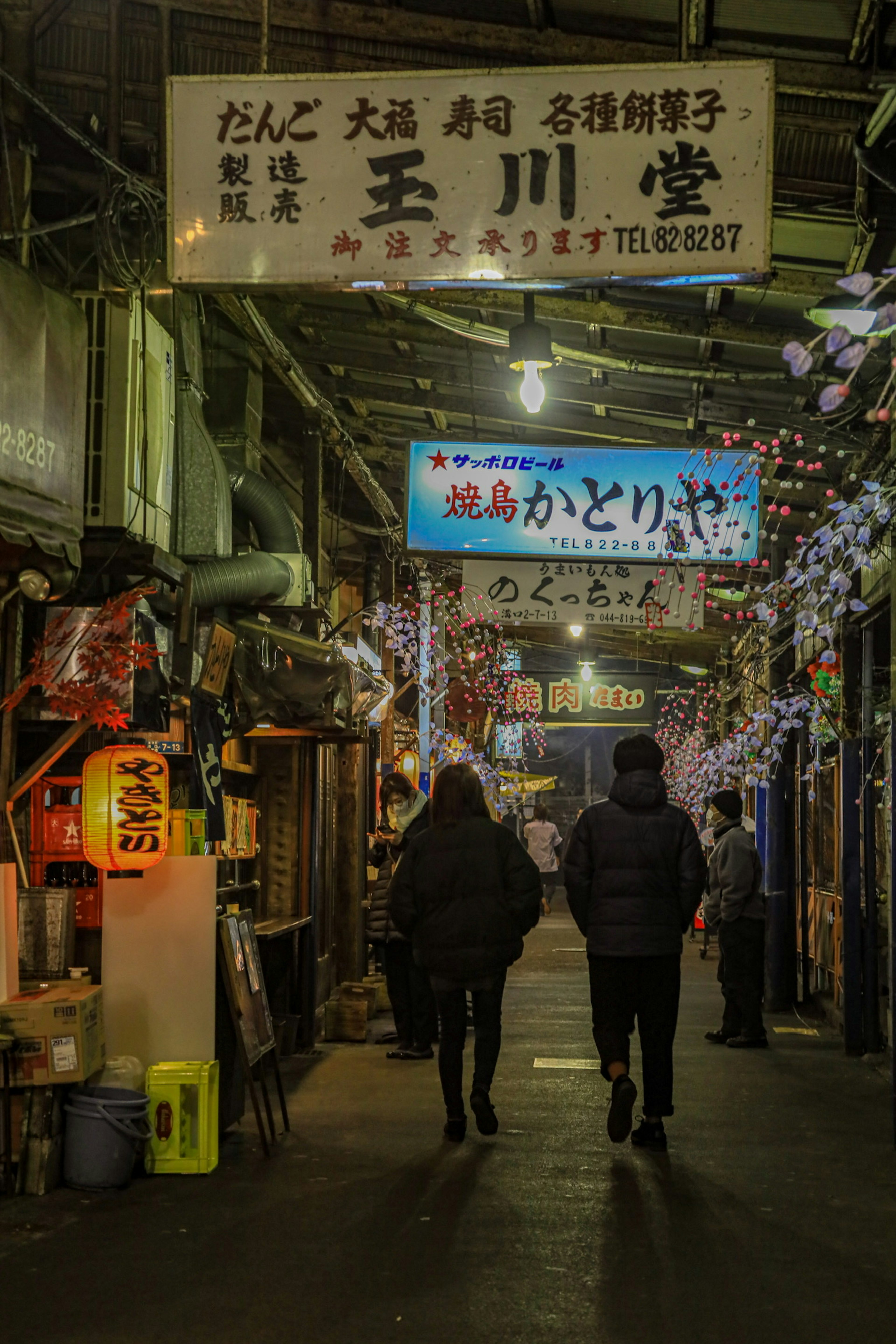 Night scene of people walking in a lively street lined with food stalls