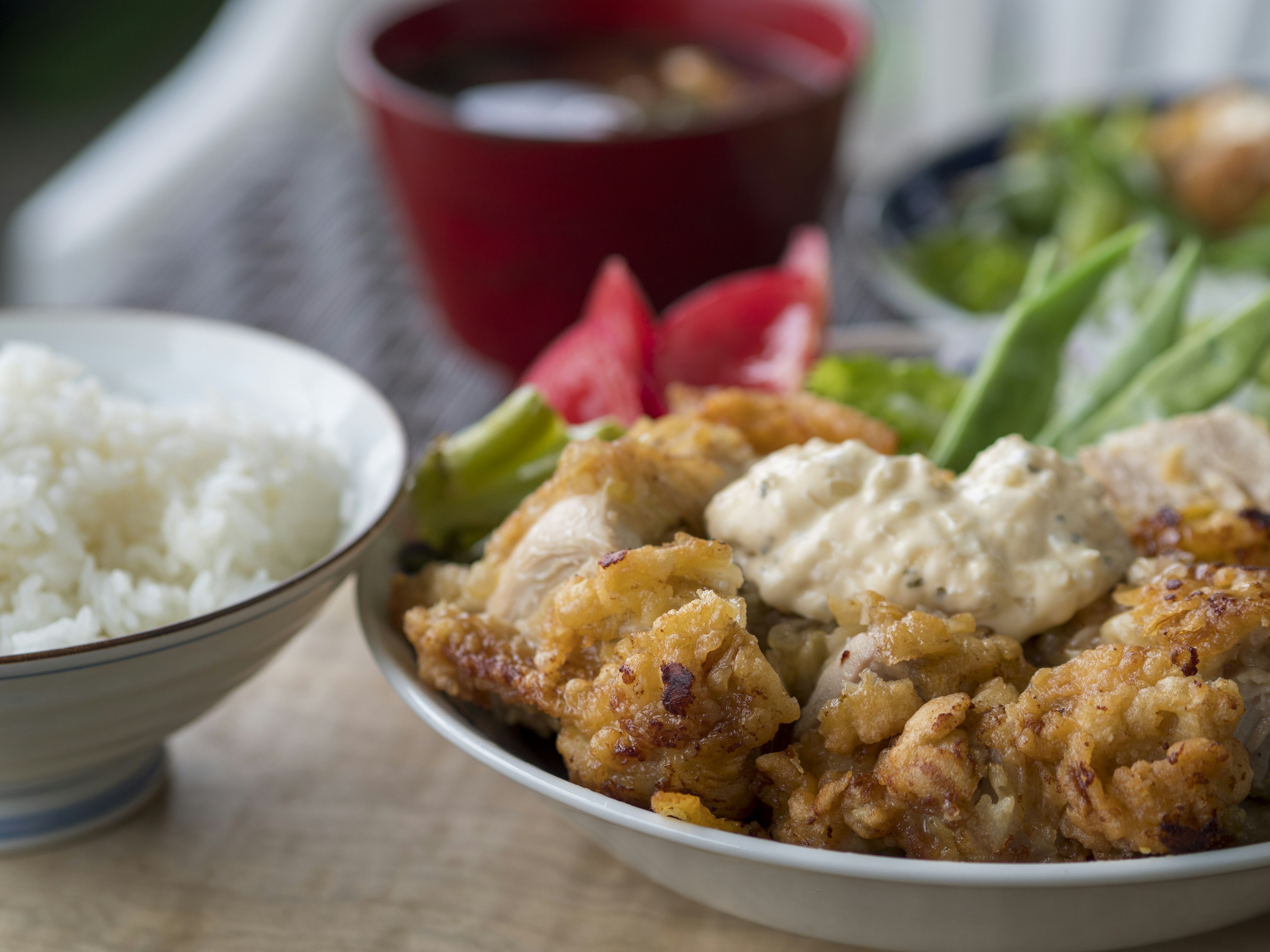 Plate of crispy fried chicken with rice and side dishes including soup and salad