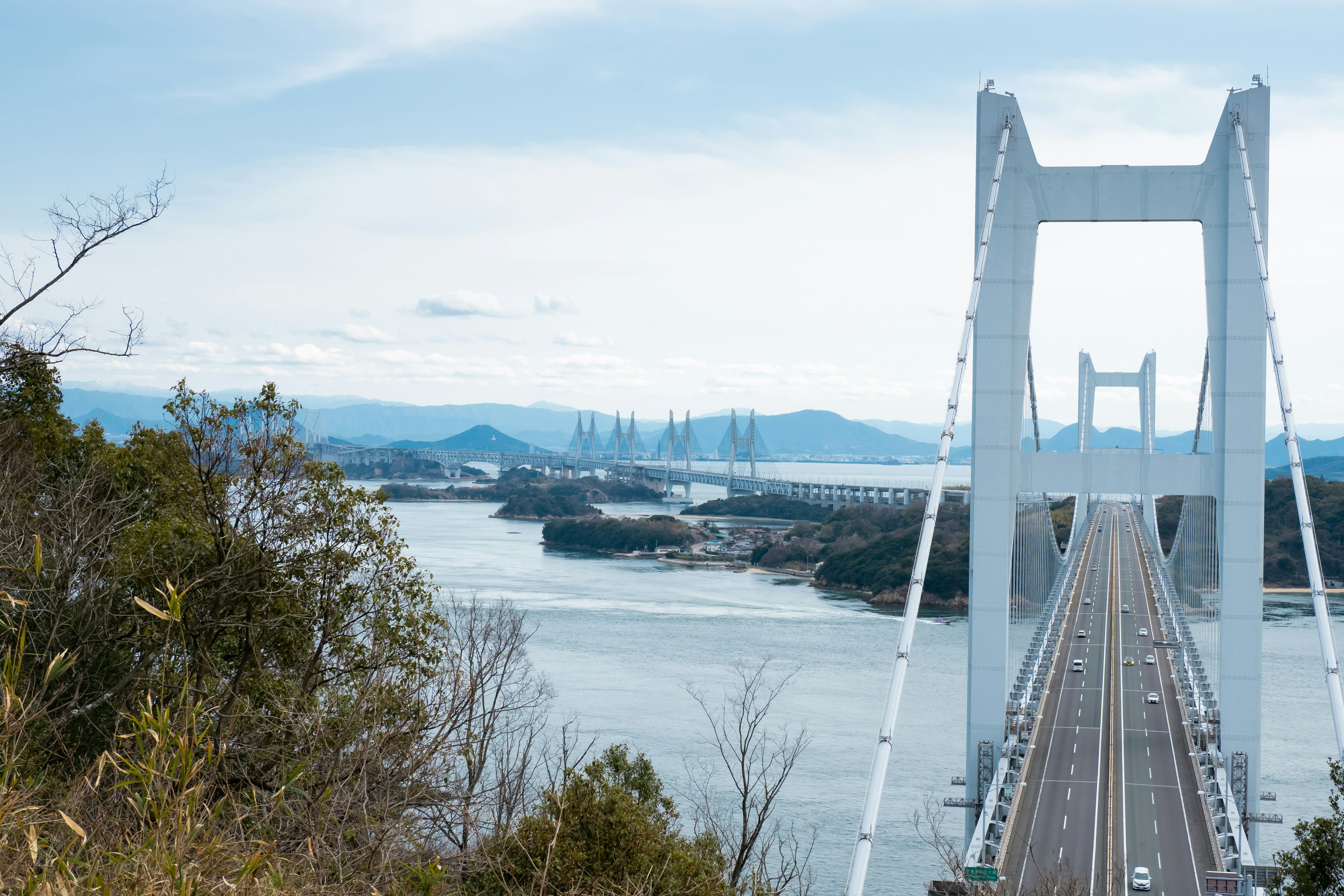 A white bridge stands against a blue sky and river landscape