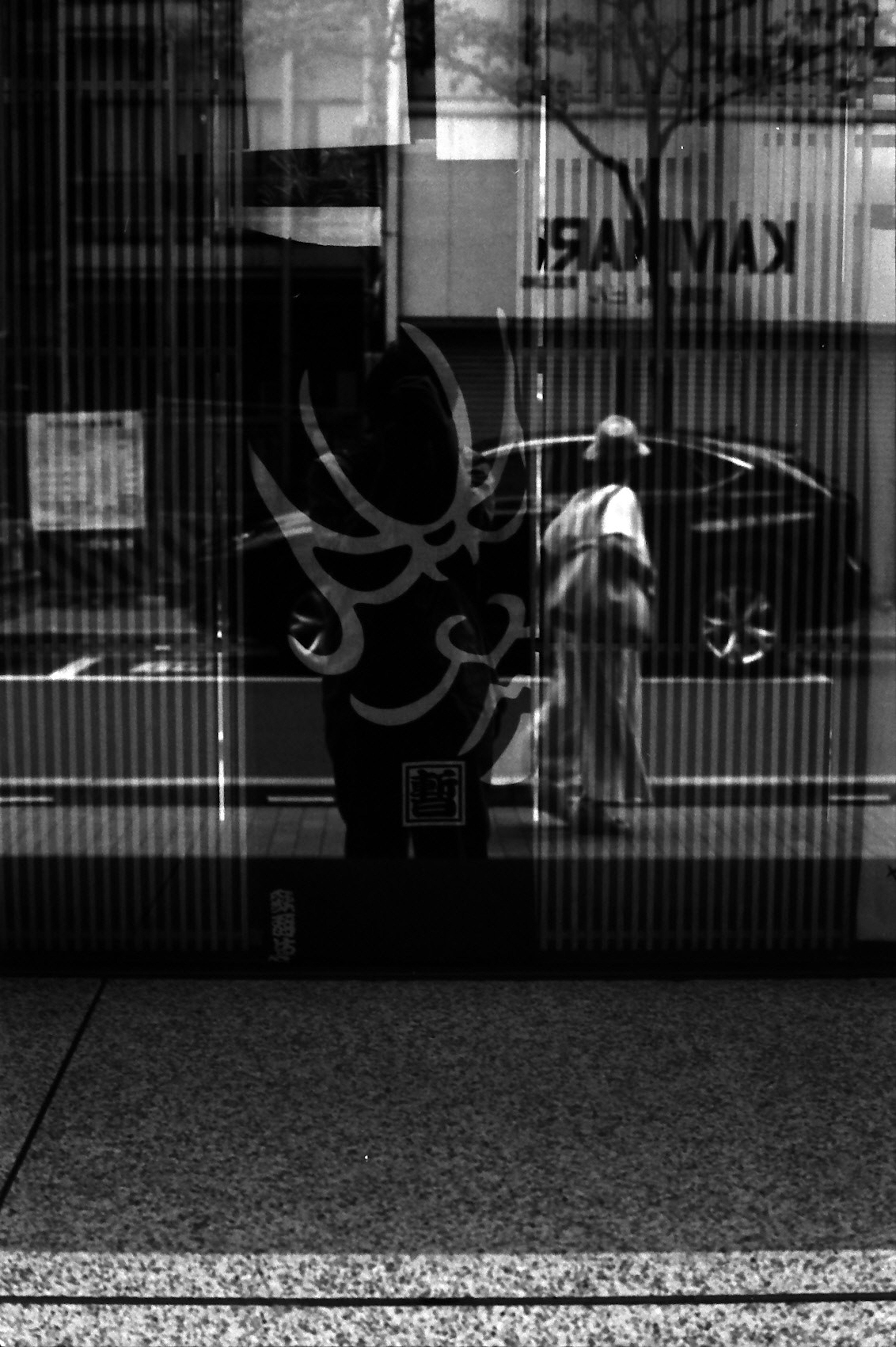 Reflejo de una persona y un coche en vidrio rayado en blanco y negro