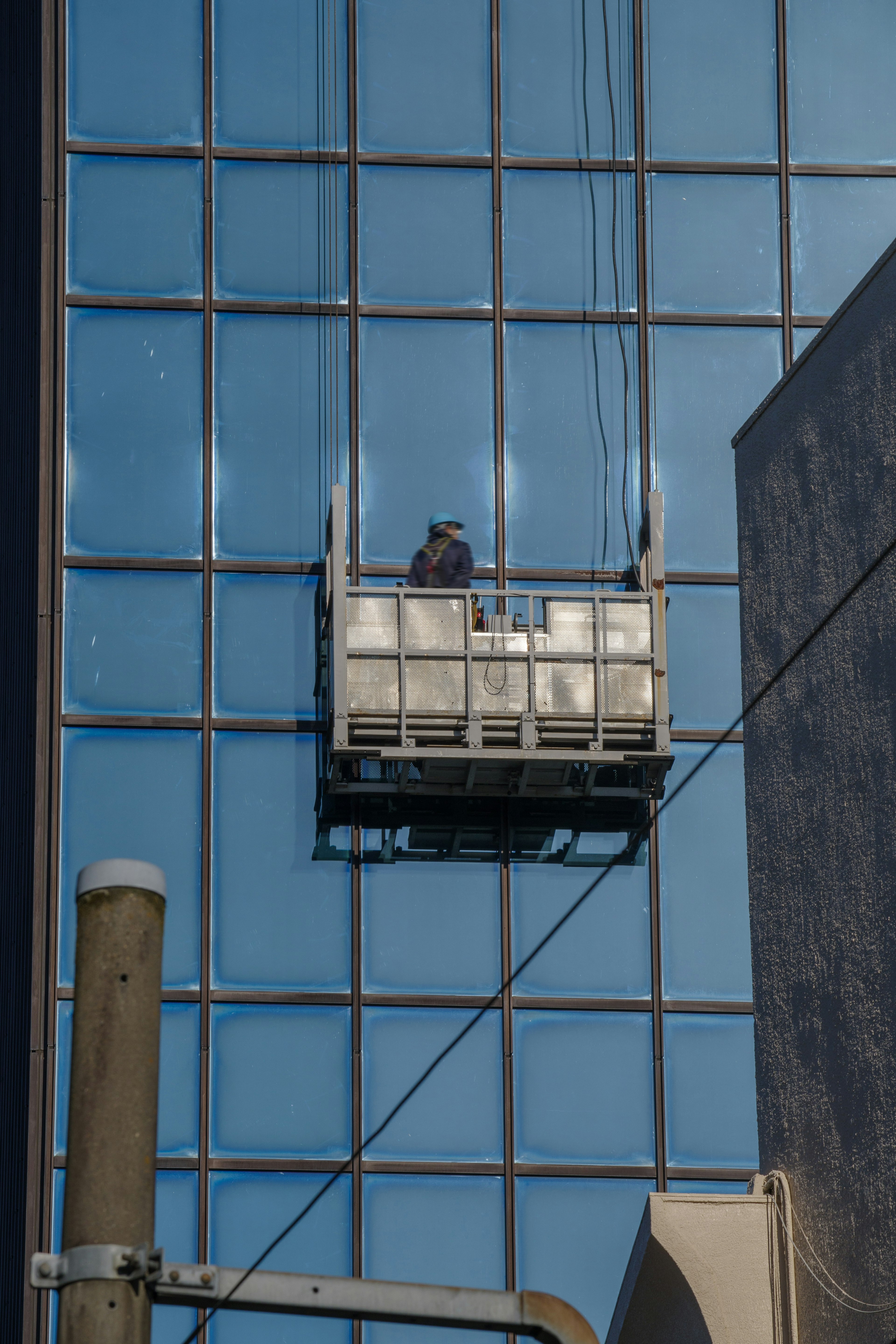 Trabajador en una plataforma limpiando ventanas de un edificio de vidrio