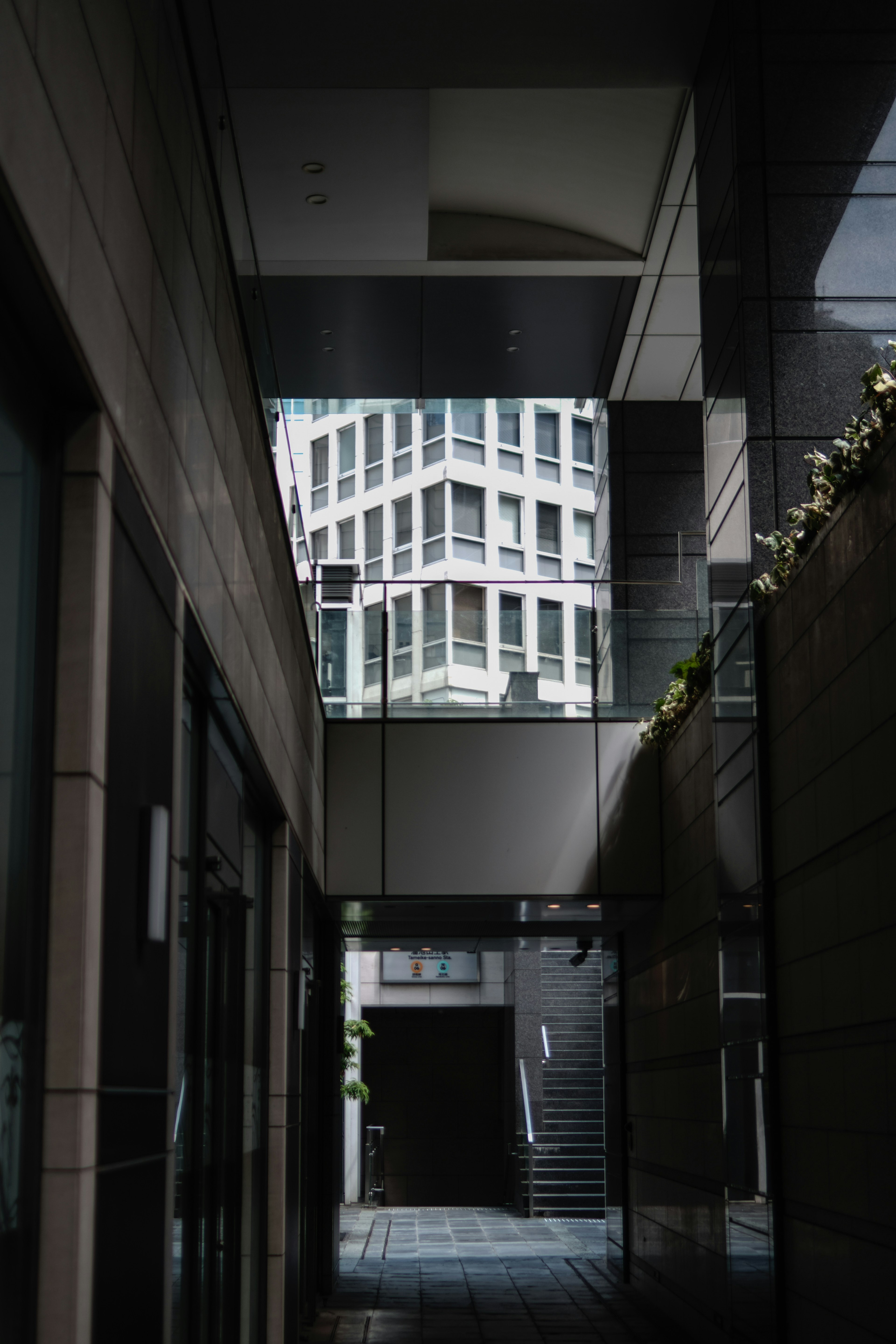 Vista del reflejo de un edificio moderno desde un callejón con escaleras