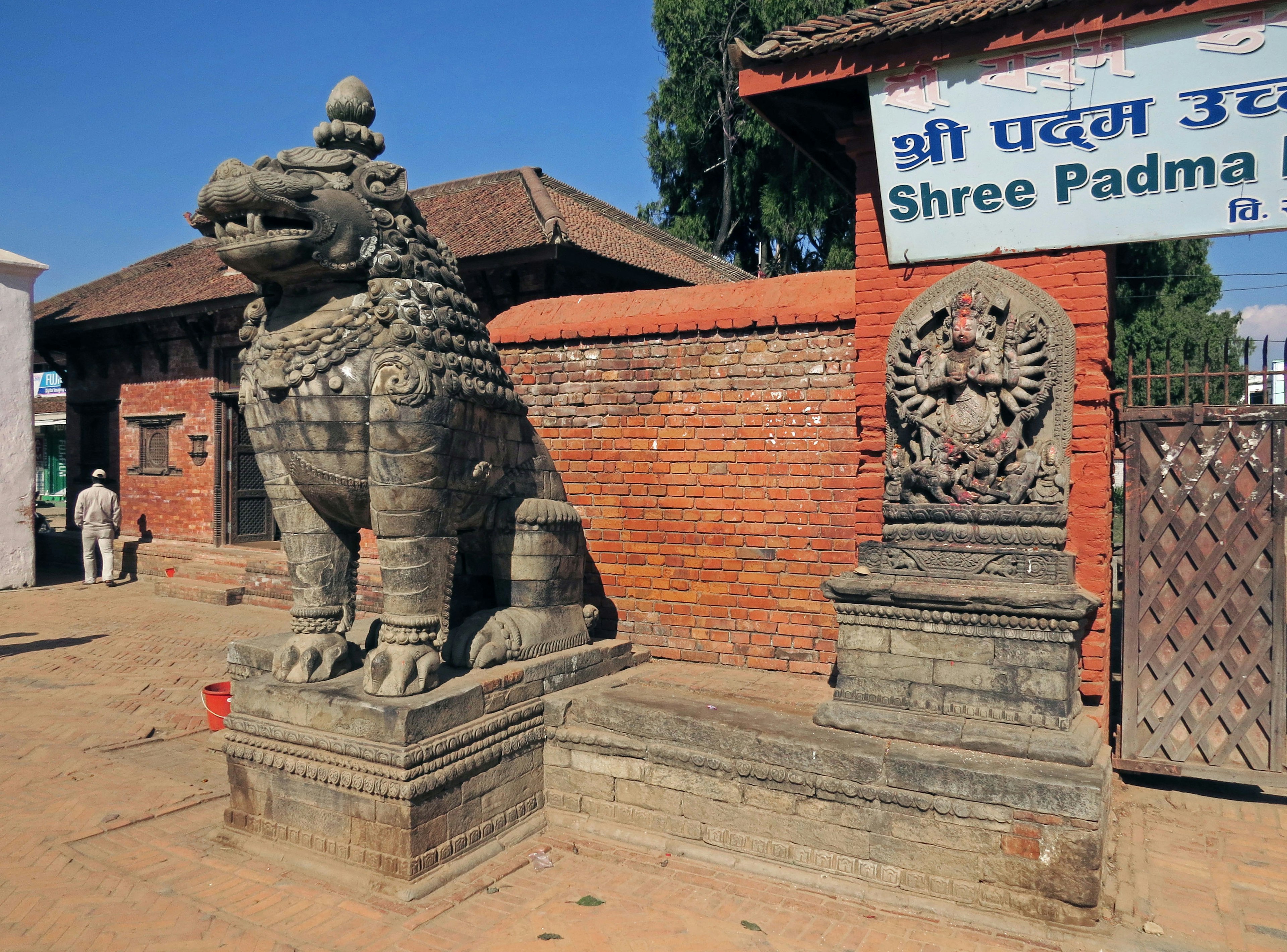 Scultura di leone in pietra e statua di divinità davanti al cartello Shree Padma