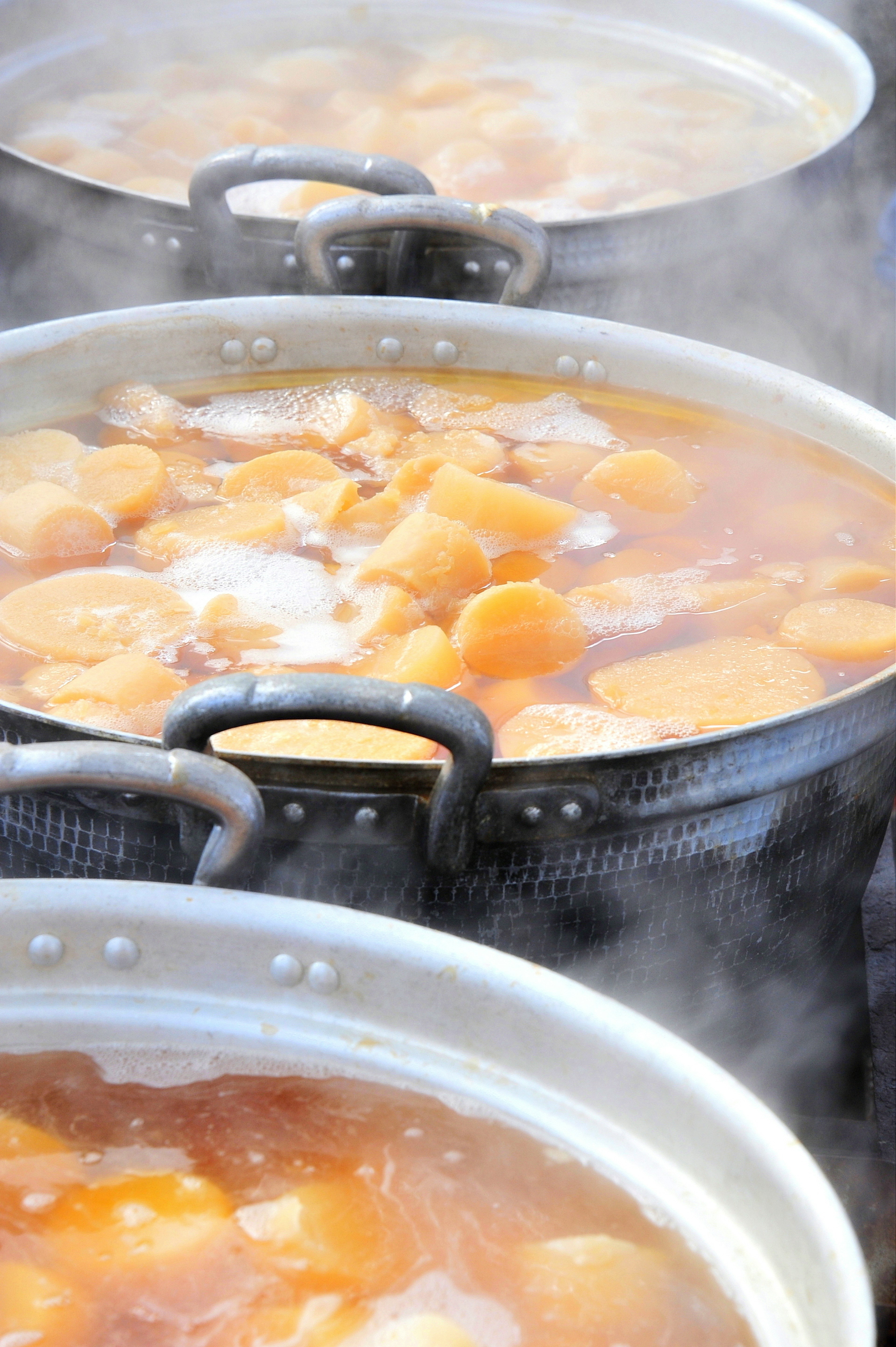 Steaming pots of orange vegetable or fruit soup