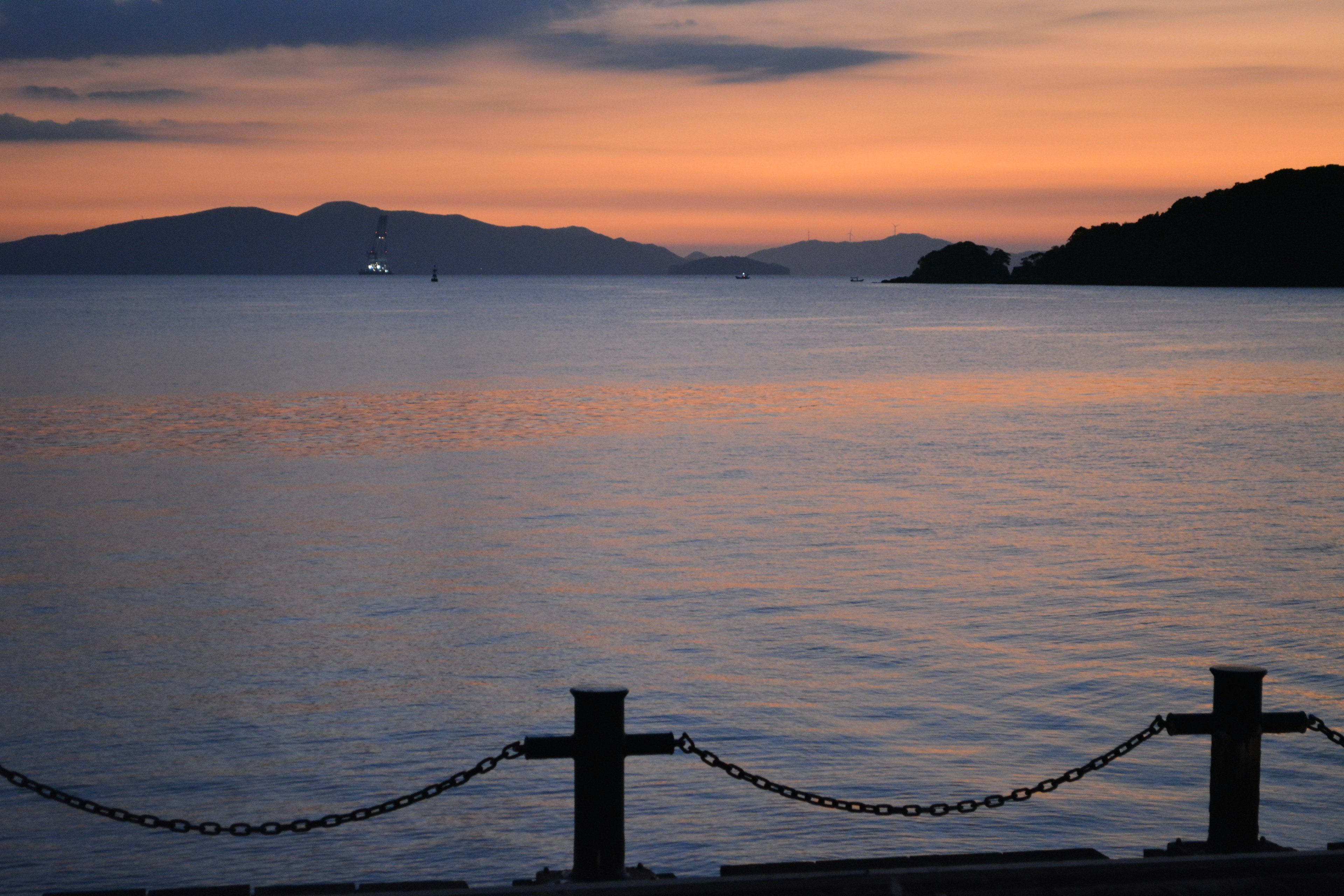 夕焼けに照らされた静かな海と山のシルエット