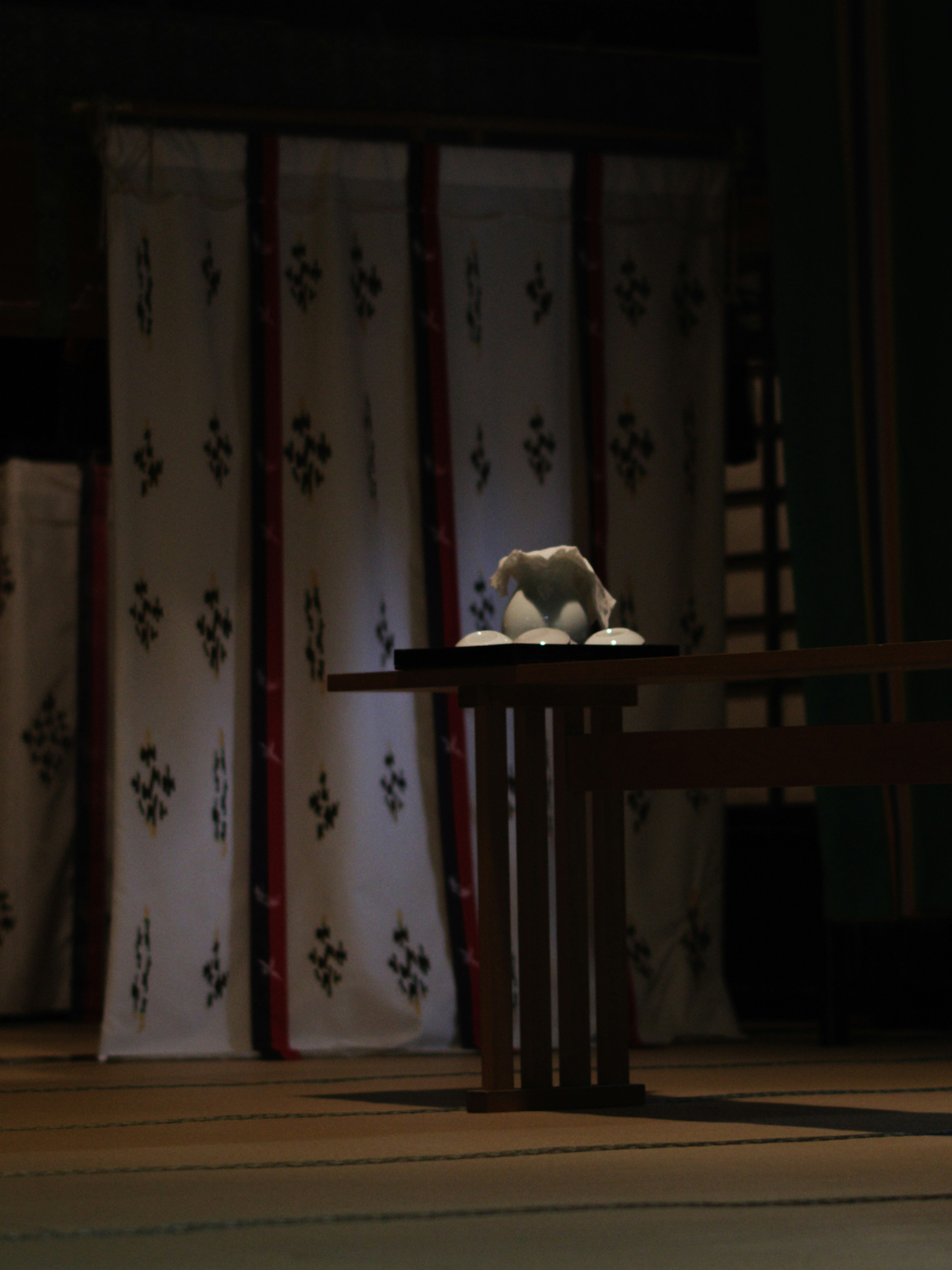 A small object on a white cloth with patterned curtains in the background