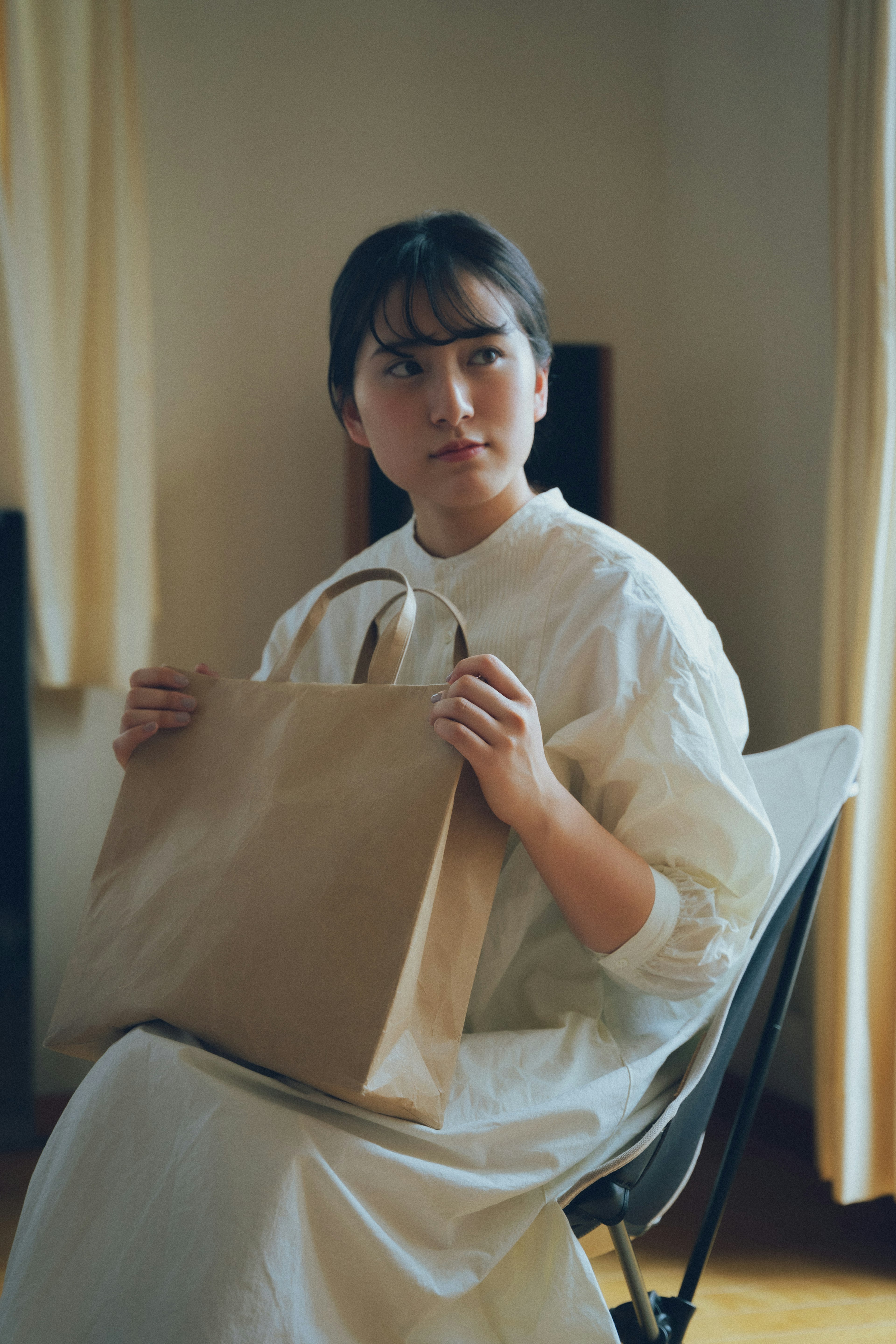 Une femme assise sur une chaise tenant un sac en papier brun