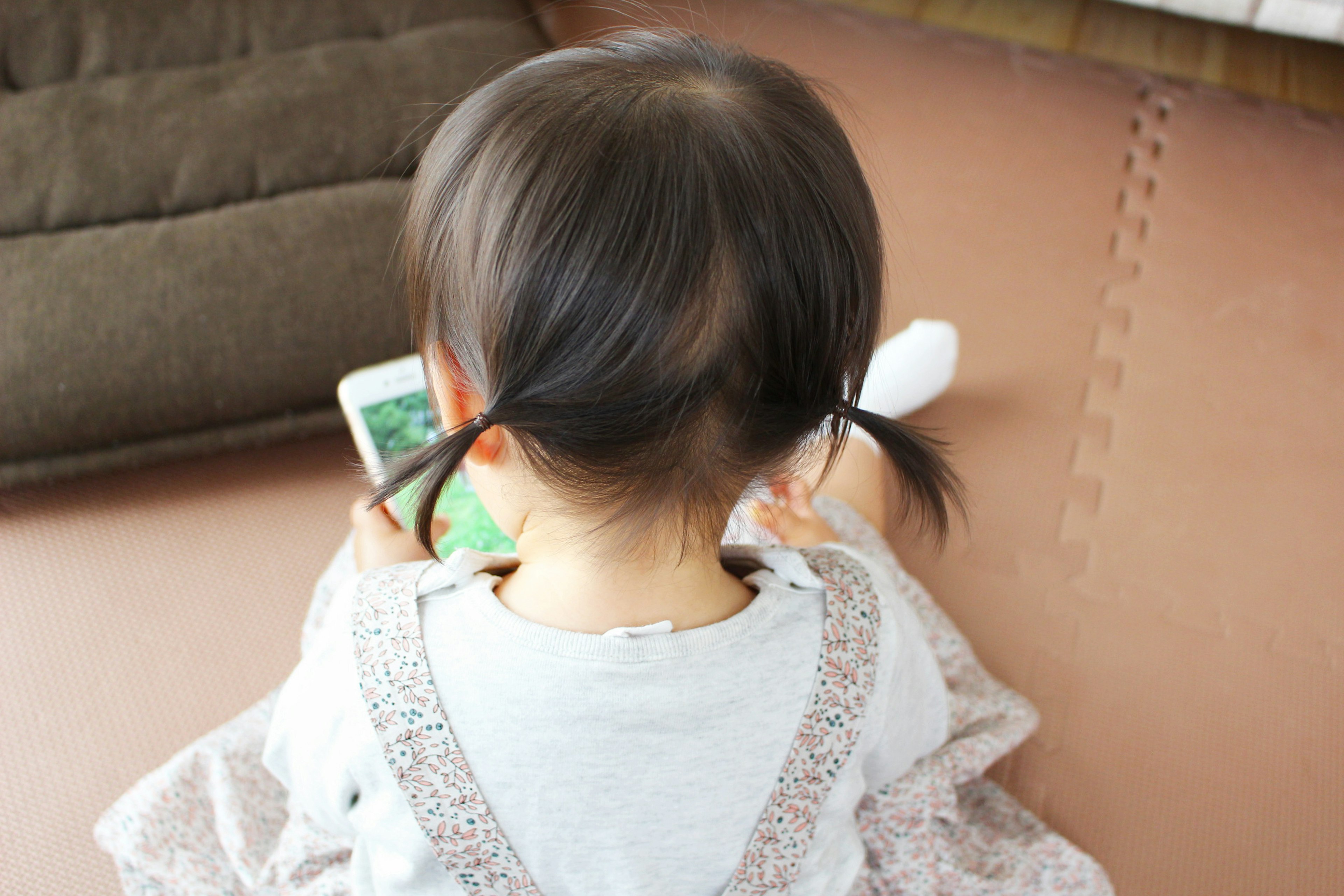 Child sitting on a floor using a smartphone