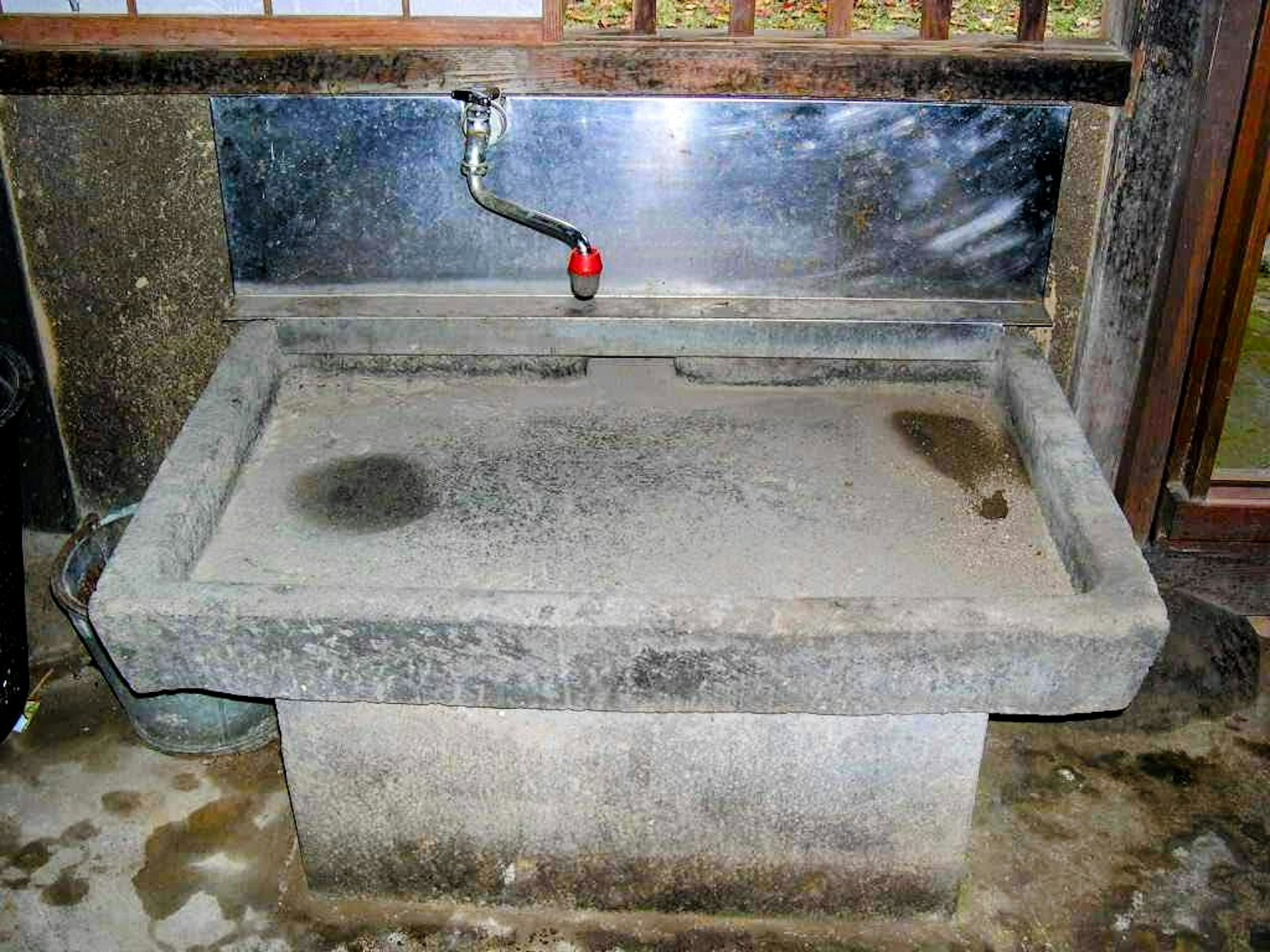 A simple stone washbasin with a metal faucet