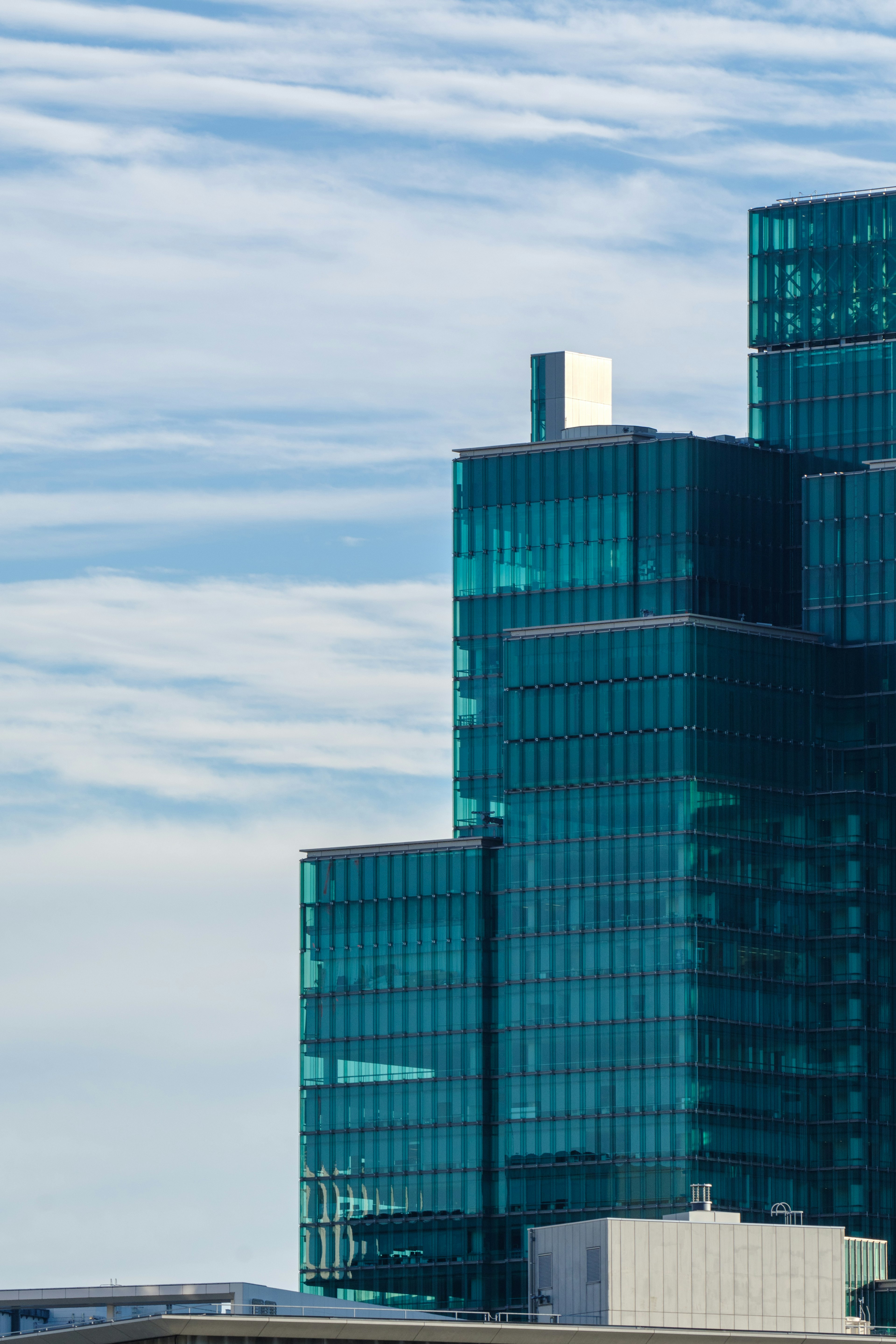 Part of a modern skyscraper with blue glass and cloudy sky