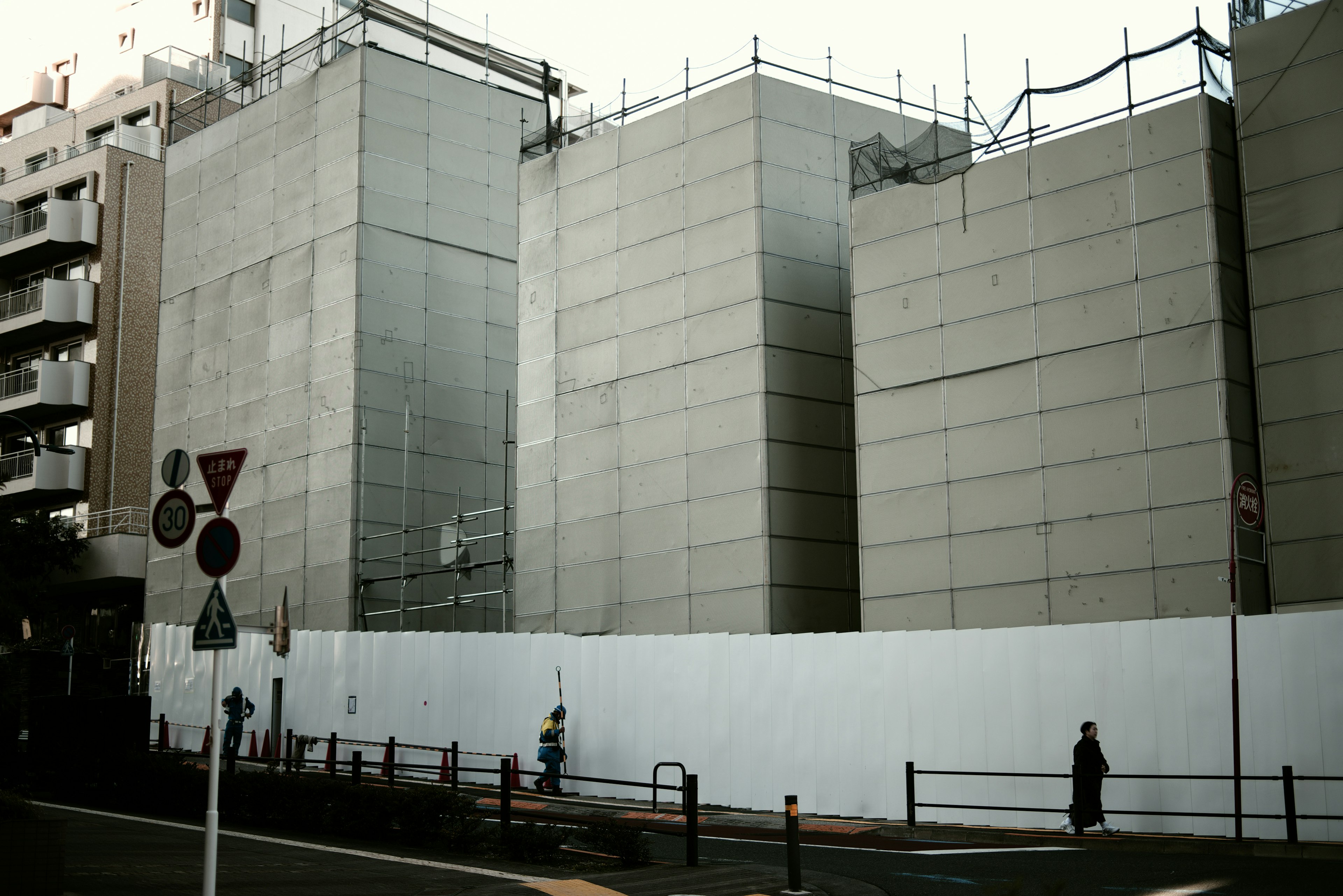 Street view featuring concrete structures under construction with white fencing