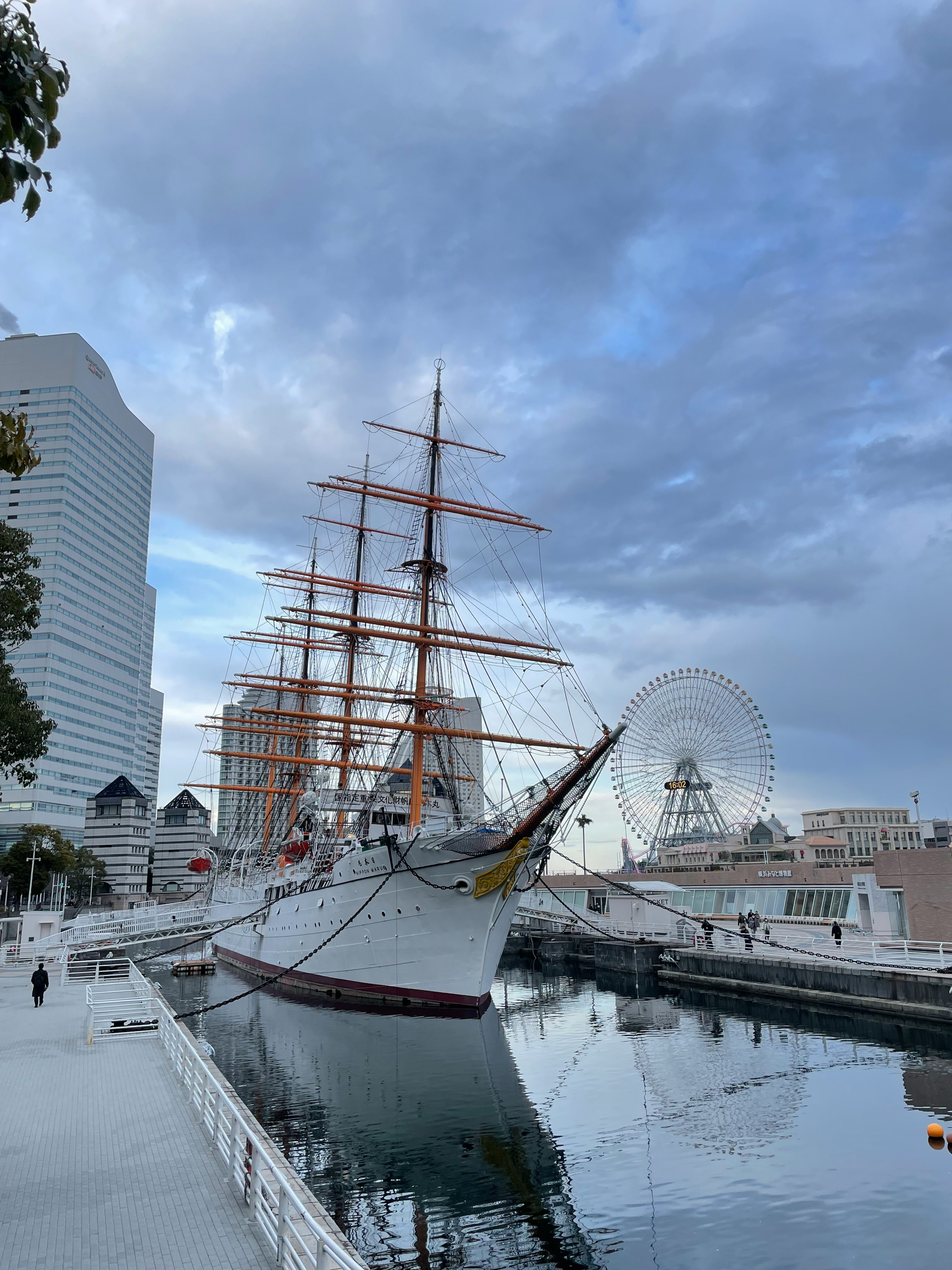 A tall ship docked in Yokohama harbor with skyscrapers in the background