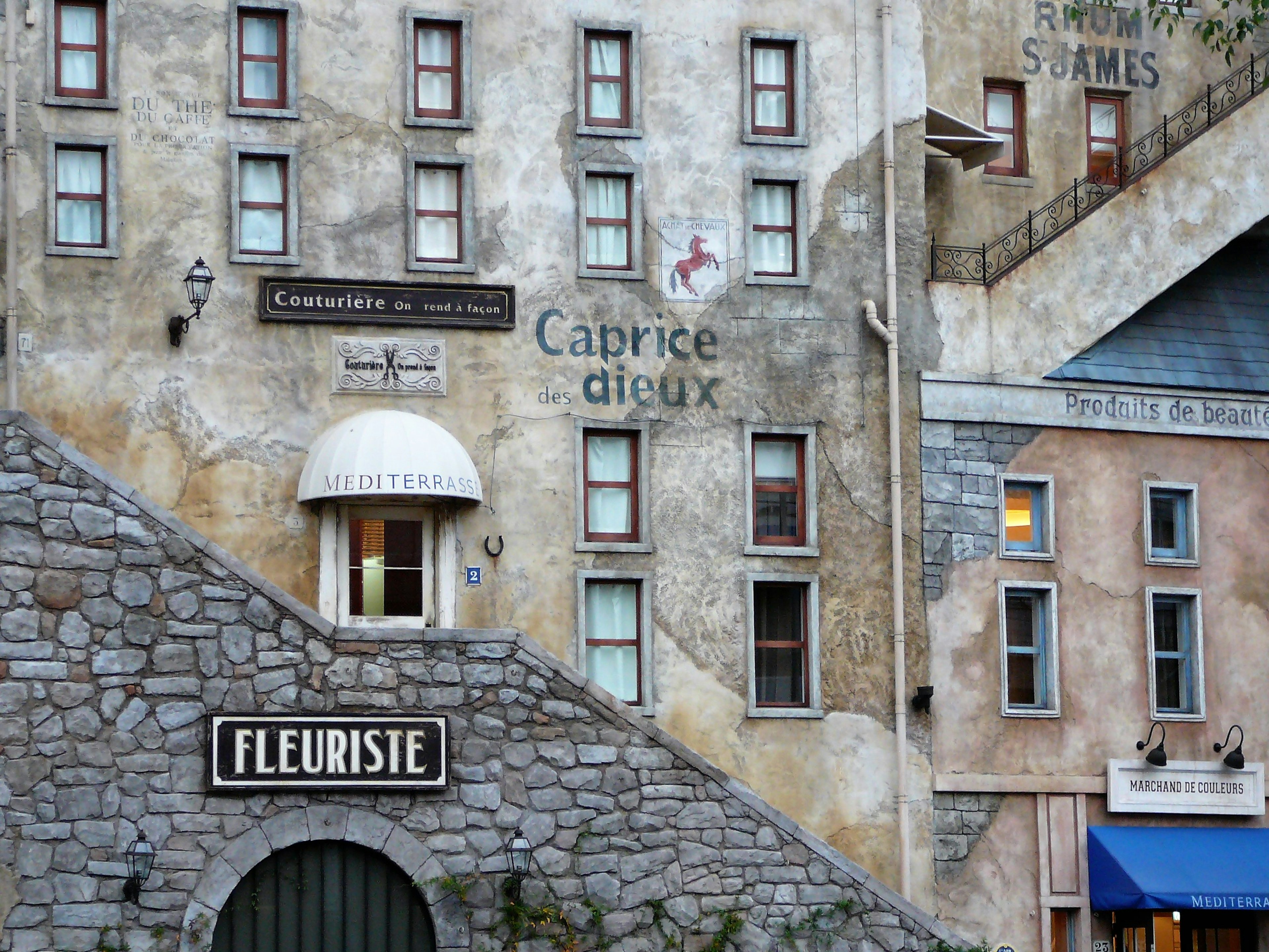 Stone building wall with French signs and vintage window designs