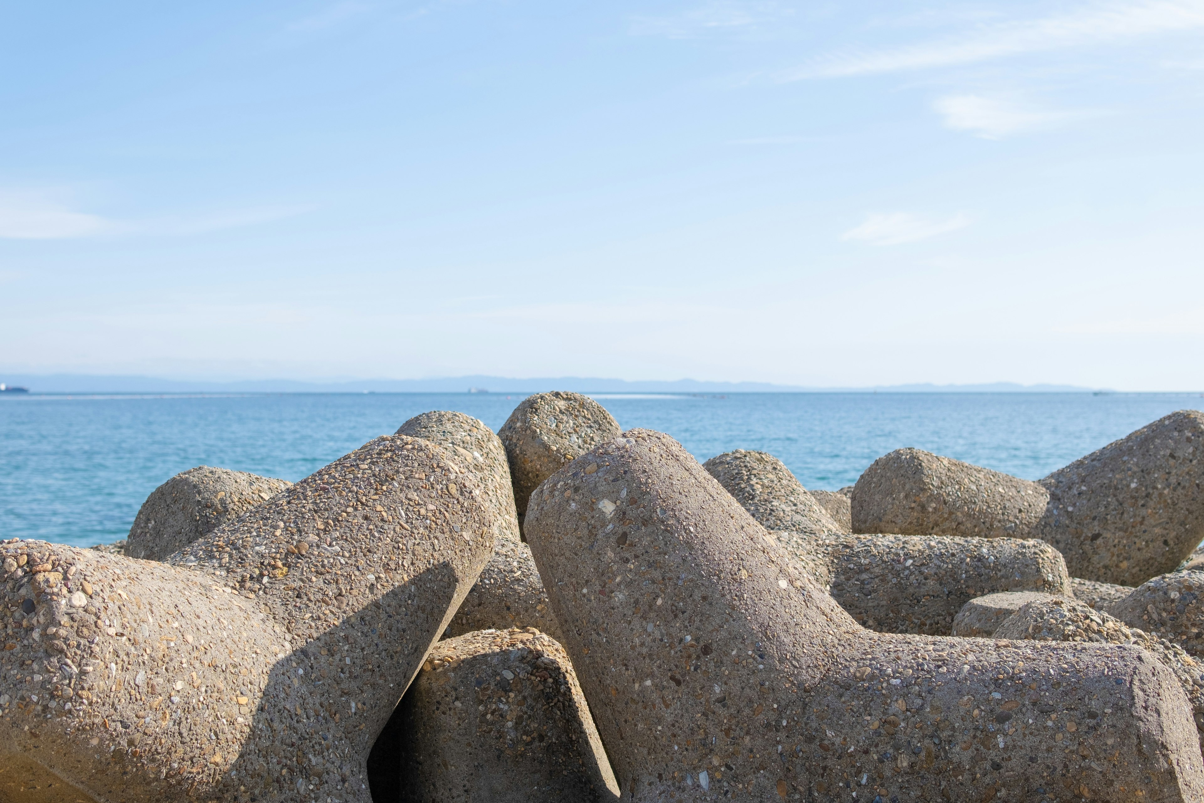 Concrete breakwater structures on a coastline with a clear blue sky