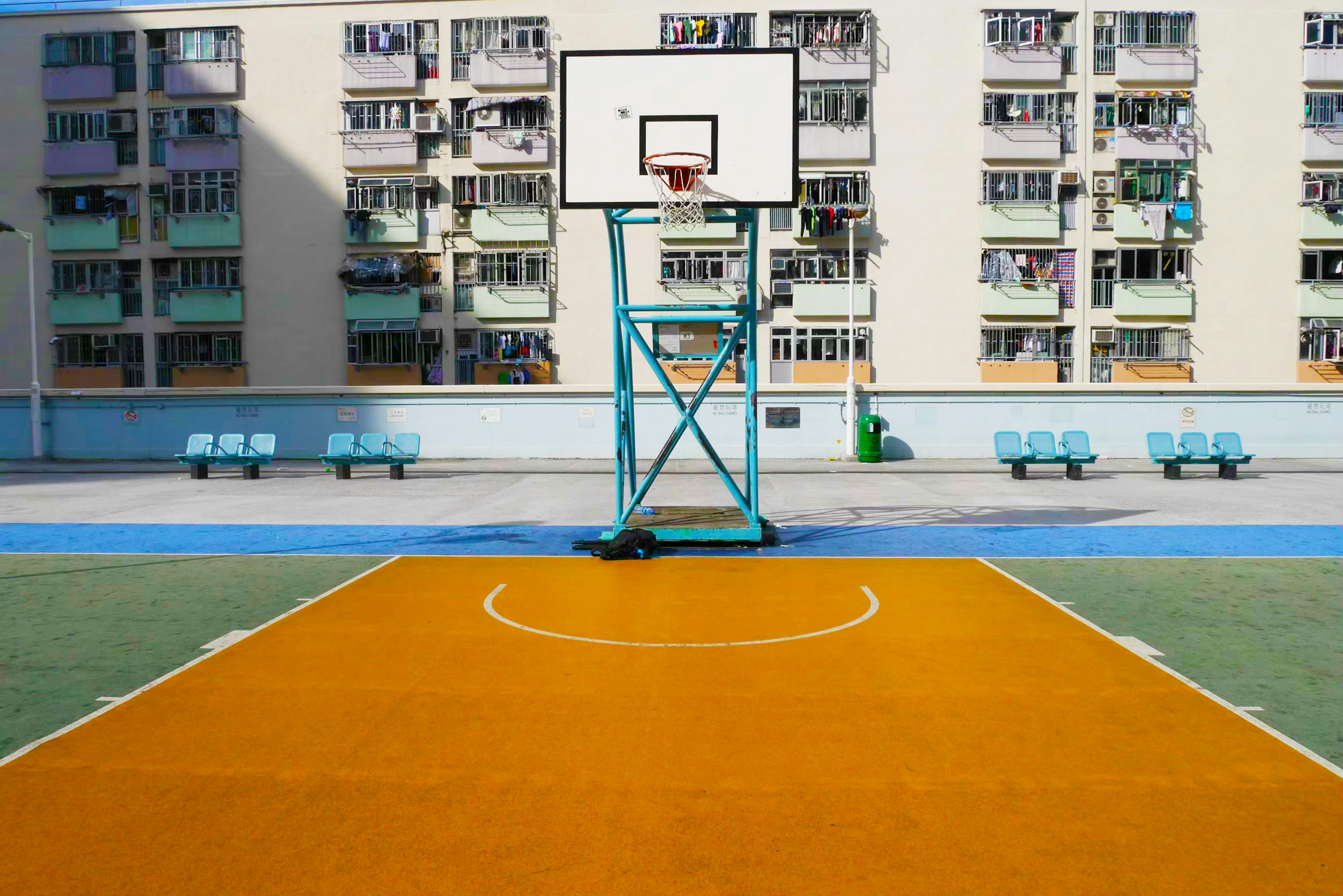 Orange basketball court with a hoop and apartment buildings in the background