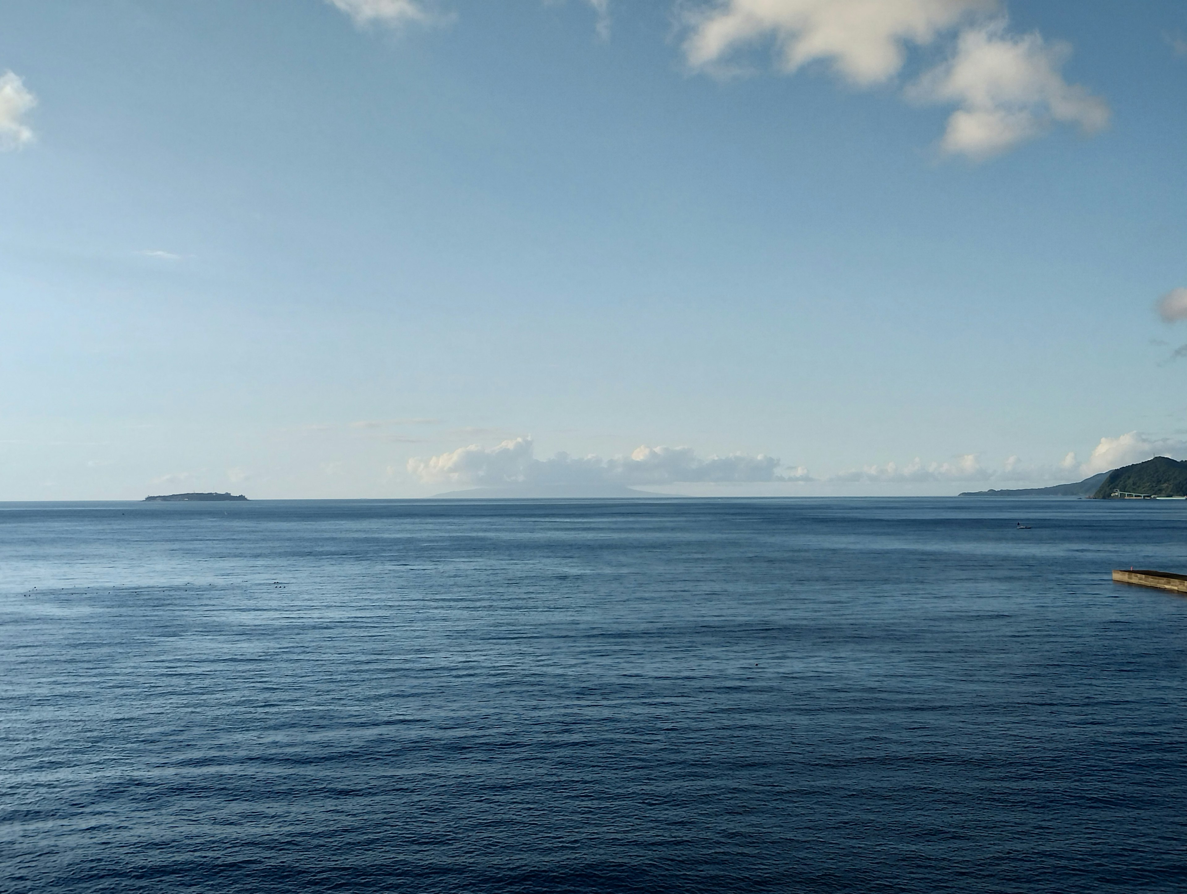 Paesaggio sereno con un oceano blu e cielo con un'isola in lontananza