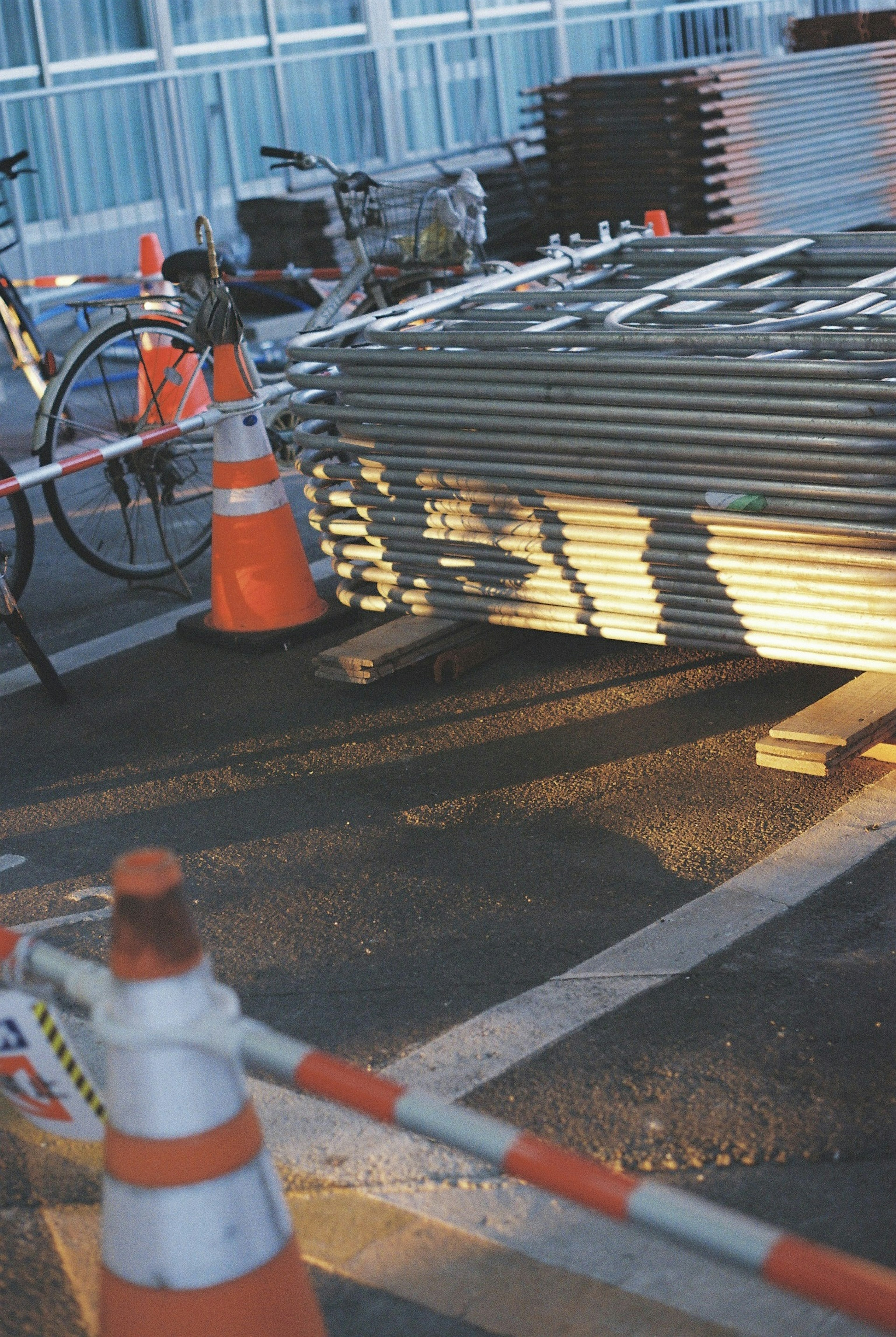 建設現場の安全標識とオレンジ色のコーンが並ぶシーン 自転車と金属製の材料が見える