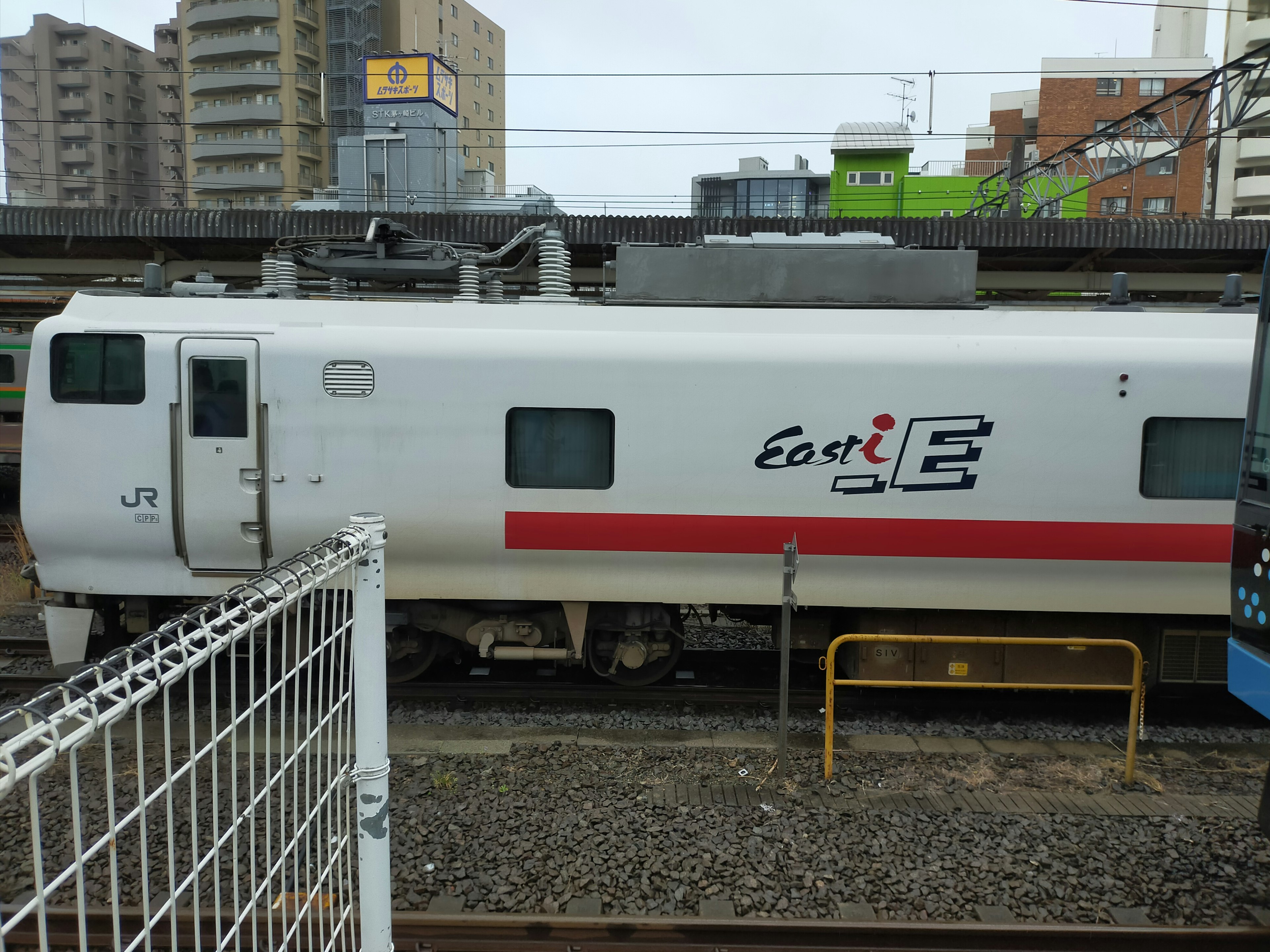 白い電車の側面に赤いストライプとロゴがある